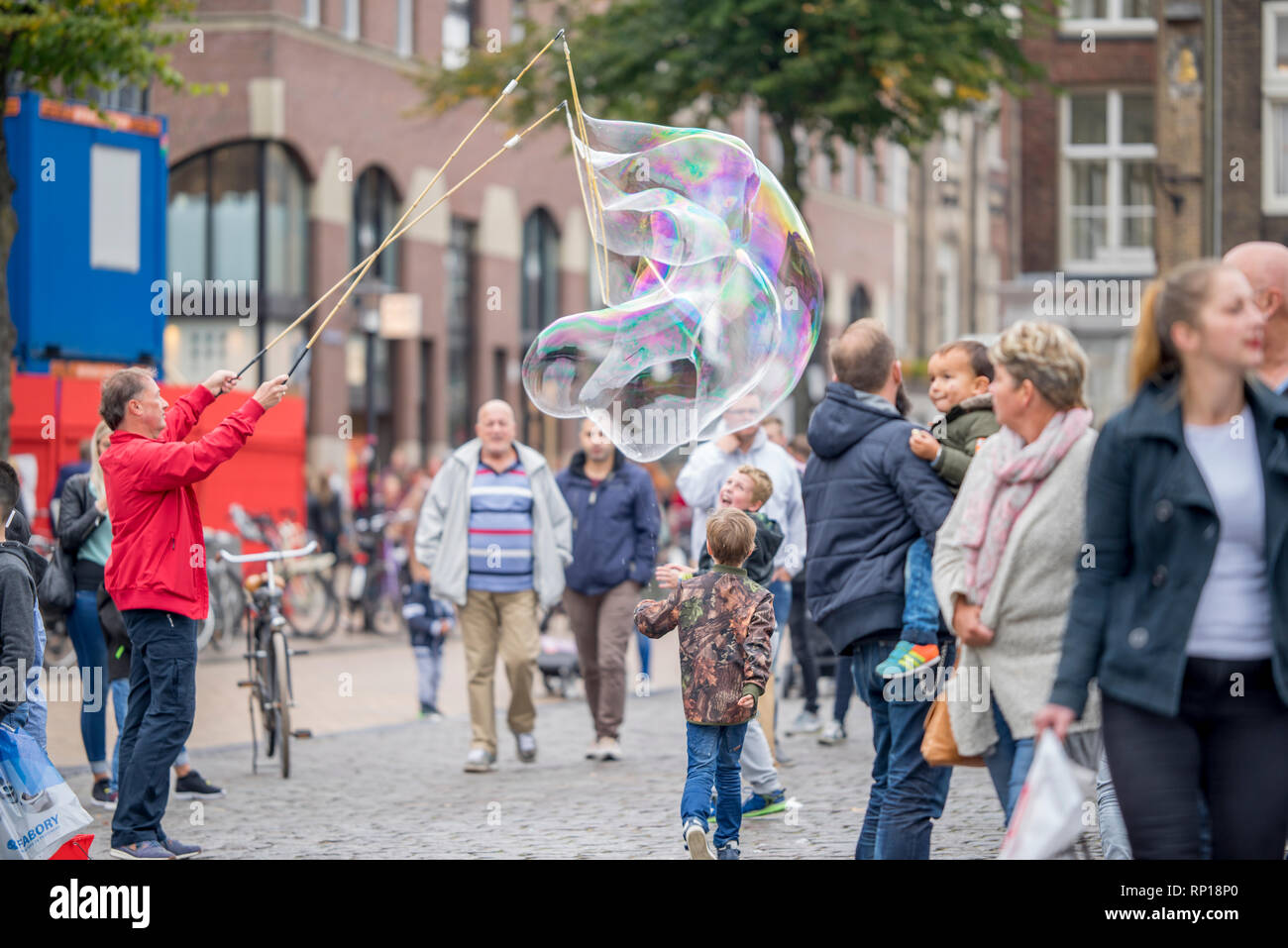 Menschen mit riesigen Seifenblasen zur Unterhaltung der Leute auf dem Markt und vor allem der Fänge, die Aufmerksamkeit von Kindern an der Groningen Samstag mark Stockfoto