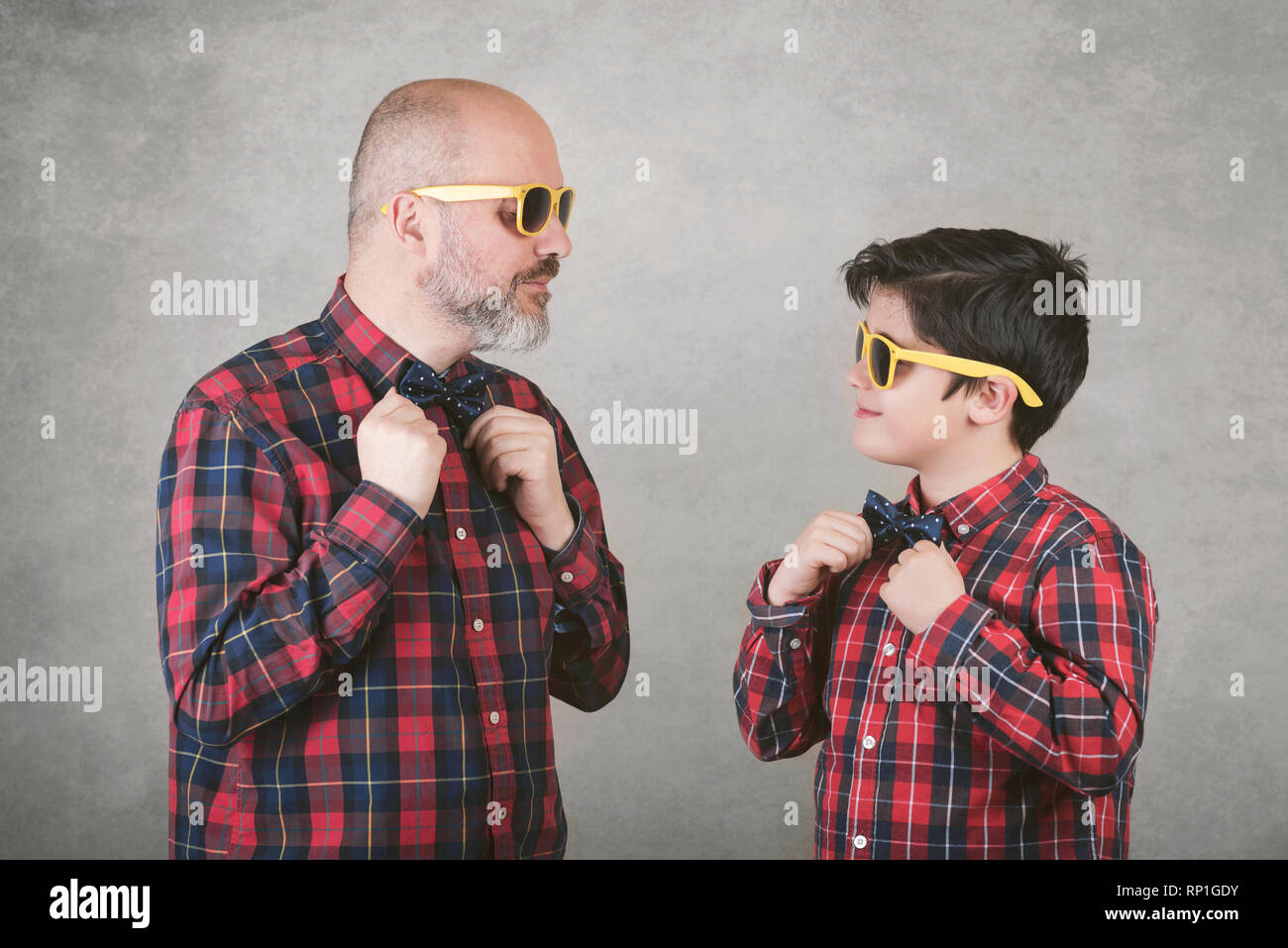 Vatertag, Vater und Sohn mit Krawatte und Sonnenbrille vor grauem Hintergrund Stockfoto