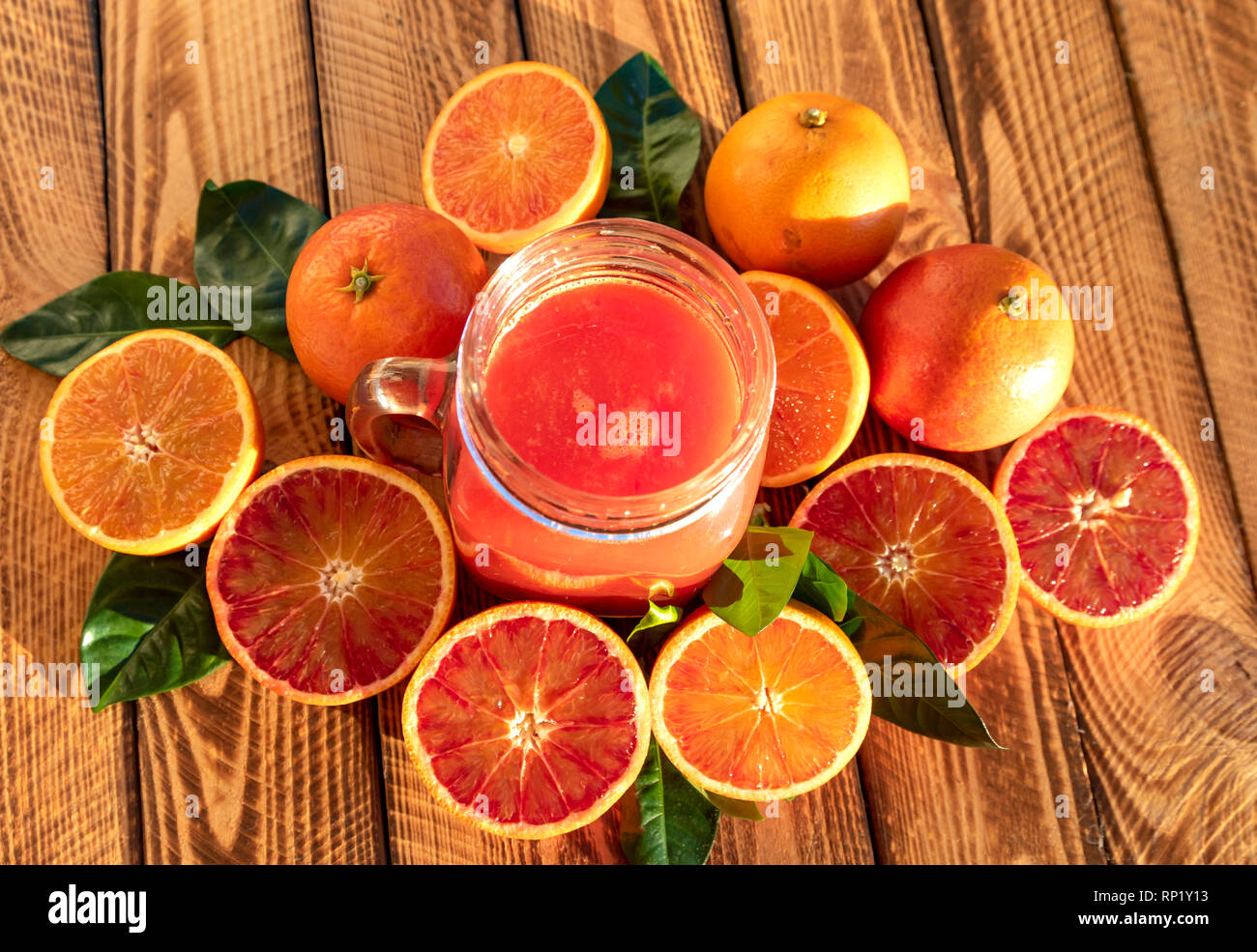 Blutorangen Saft mit frischem Obst auf hölzernen Hintergrund. Außenaufnahme im Sonnenschein Stockfoto