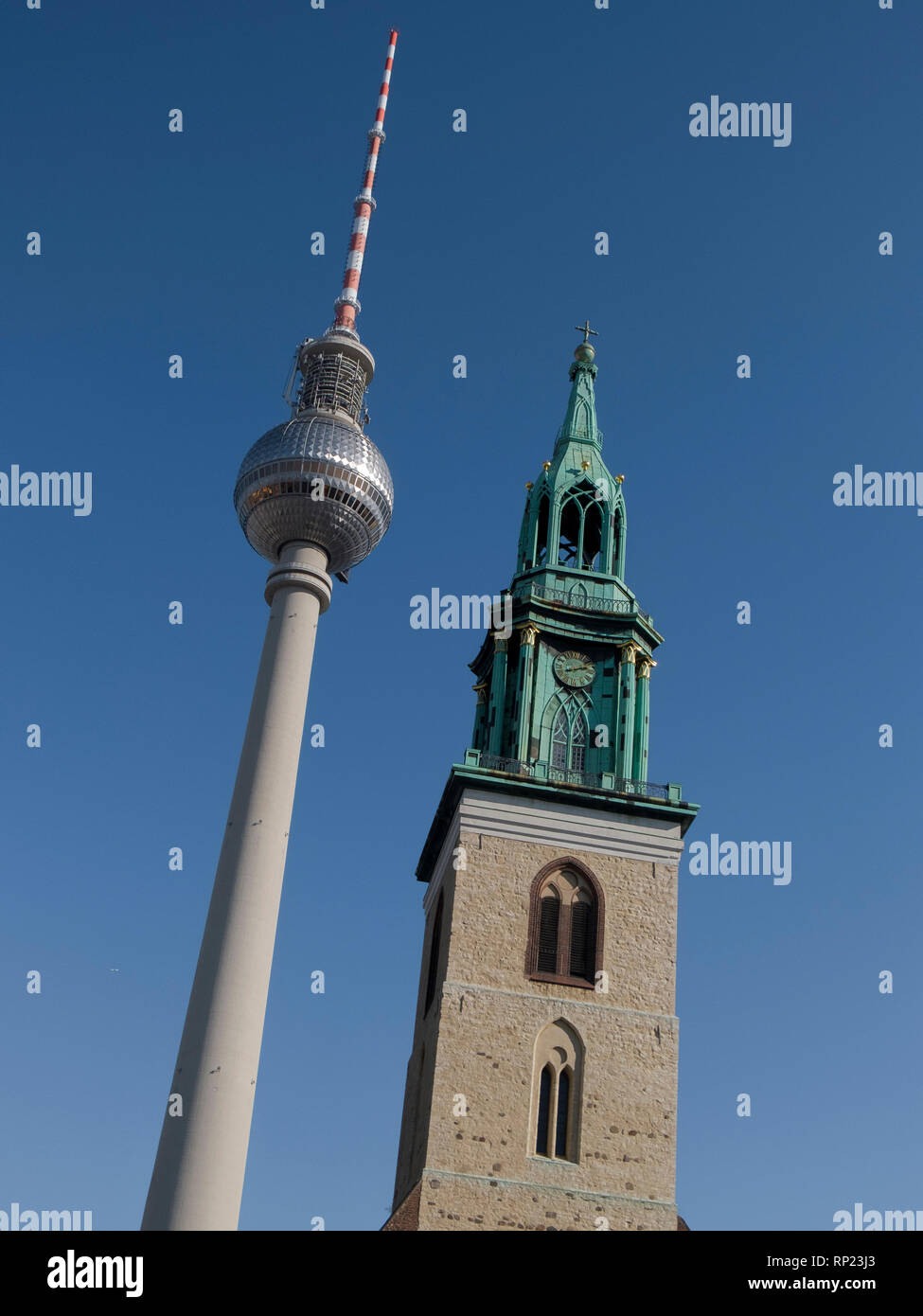 Alt trifft Neu in Berlin. Der Fernsehturm, formal in der DDR" in Berlin, neben einem alten Kirchturm. Stockfoto