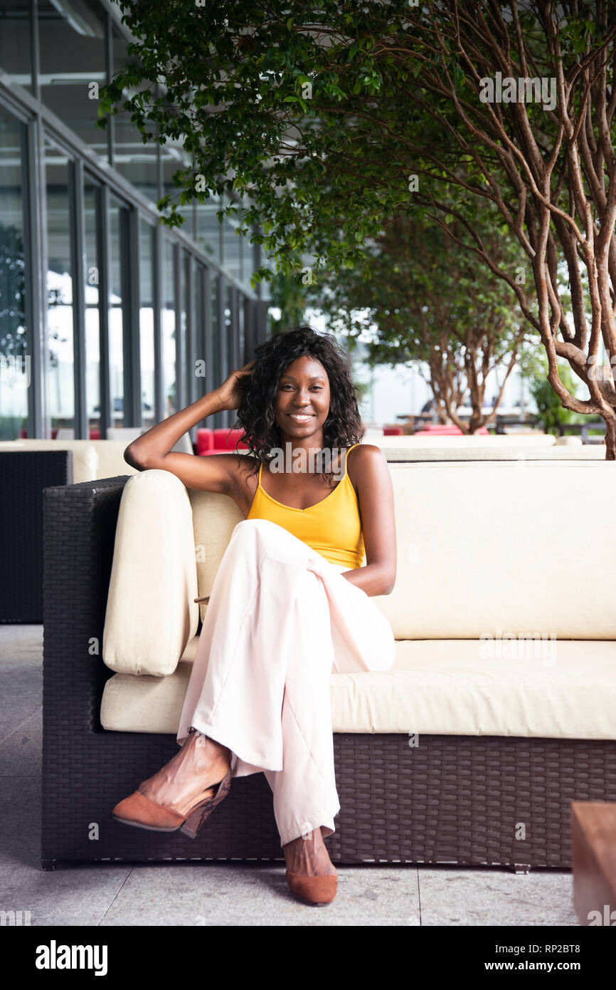 Eine attraktive, stilvolle Afrikanischen brasilianische Frau sitzt auf einem Sessel Stockfoto