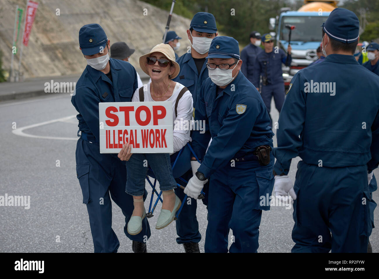 Henoko, Okinawa, Japan. 19 Feb, 2019. Die Polizei eine Frau weg vom Tor der Eine neue US Marine Corps Airbase in Henoko auf der japanischen Insel Okinawa gebaut wird. Dutzende Demonstranten, die wollen den Bau gestoppt, hatte physisch um für Lkw von der Basis, die Füllung in einem großen Teil des Meeresbodens ist um einen neuen Flugplatz zu bauen eingeben, das entfernt werden soll. Credit: Paul Jeffrey/Alamy leben Nachrichten Stockfoto