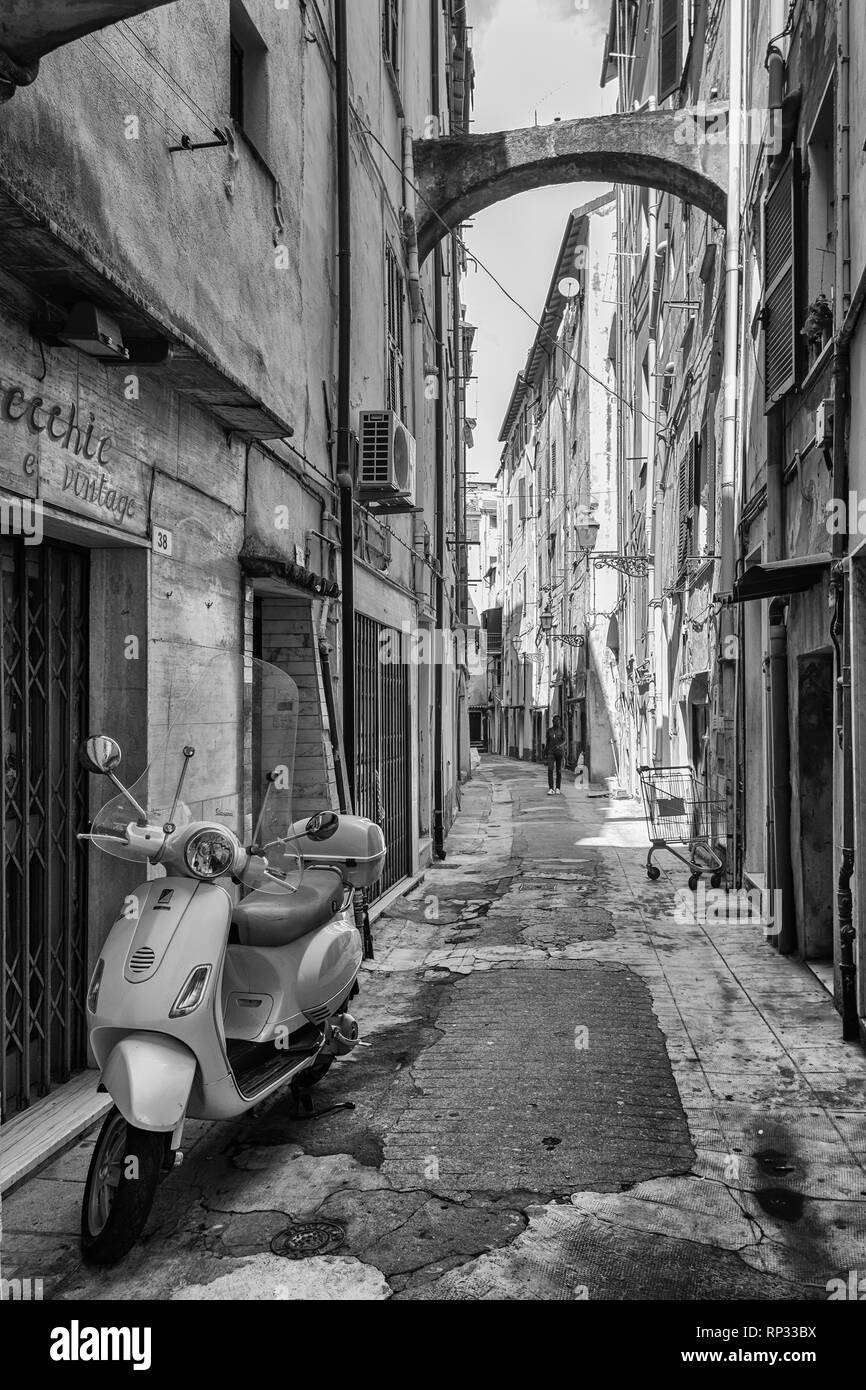 Schwarz Weiß Bild von einem Motorroller in der schmalen Straße Via Bezzecca im Zentrum der italienischen Stadt San Remo geparkt. Stockfoto