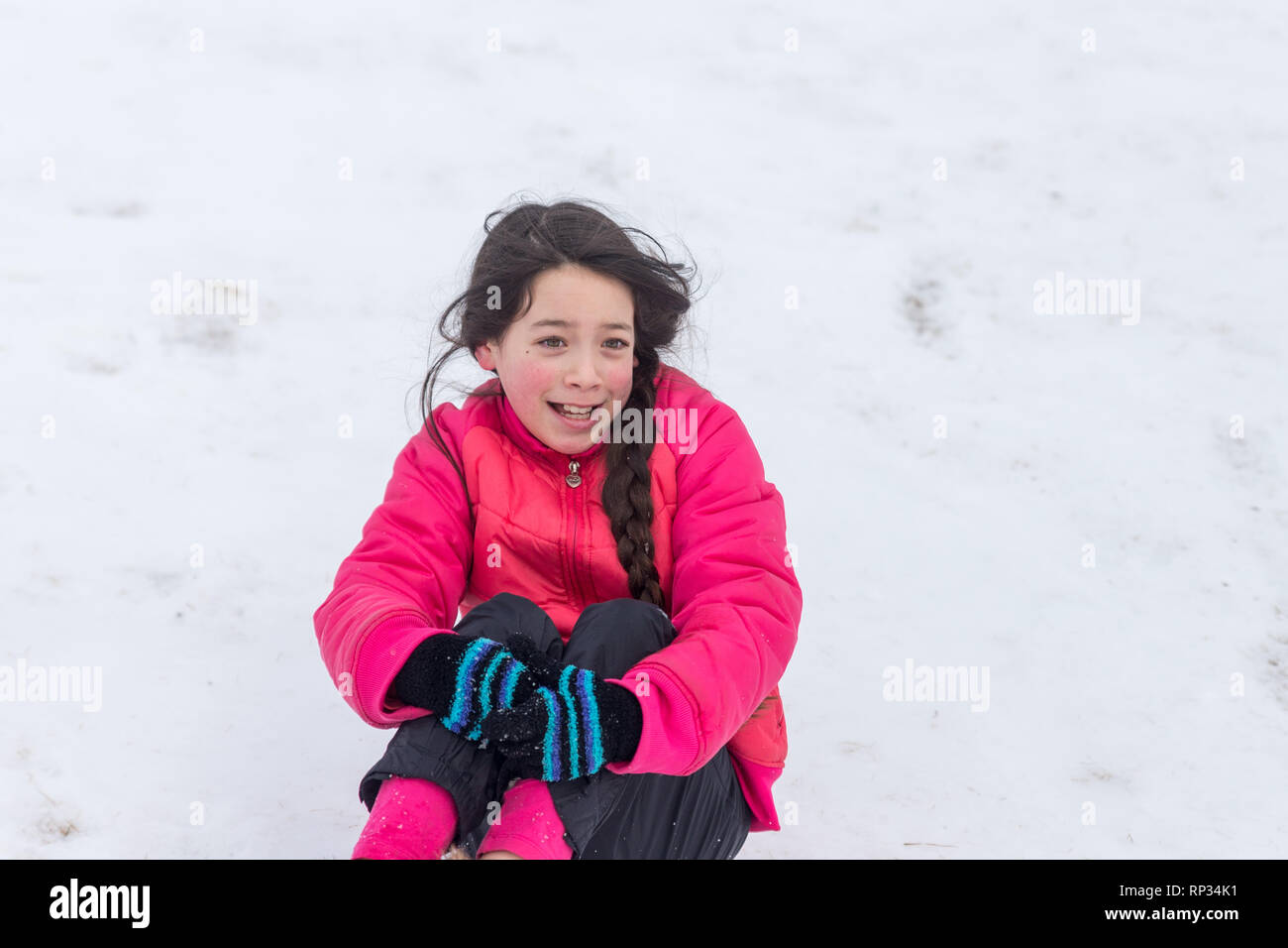 Junge asiatische Mädchen mit rosa Hut und Jacke Spielen im Schnee. Stockfoto
