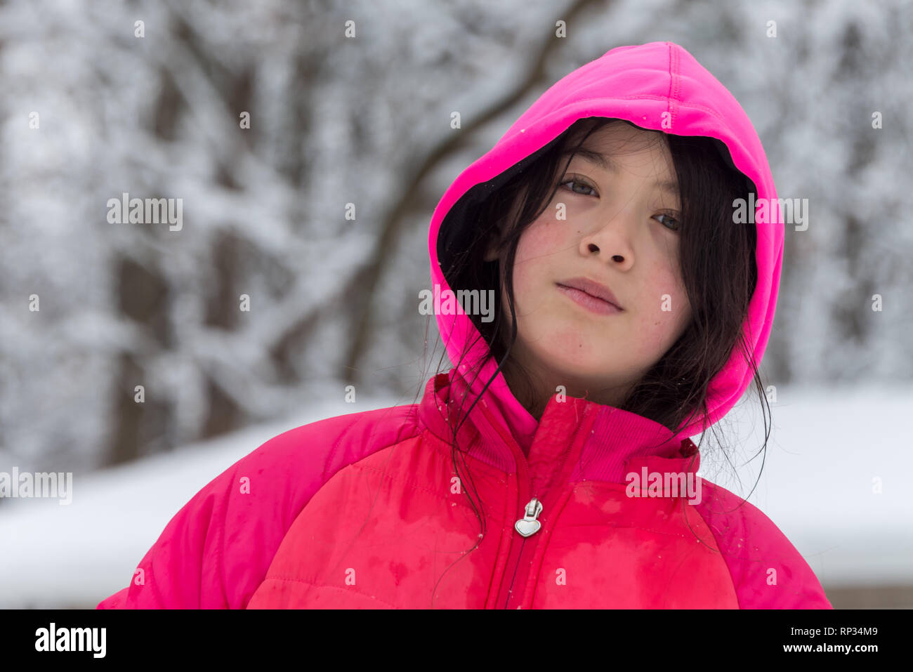 Junge Mädchen mit rosa Haube und Jacke umgeben von schneebedeckten lächelnd Stockfoto