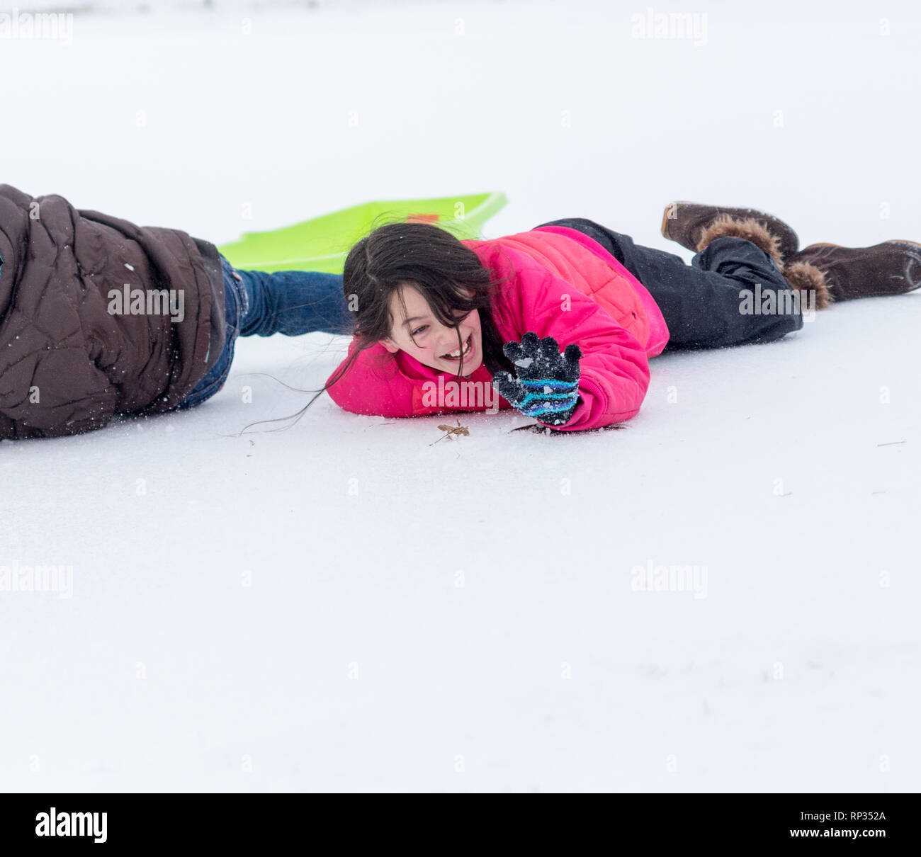 Junge asiatische Mädchen mit Schnee neben Schlitten Stockfoto