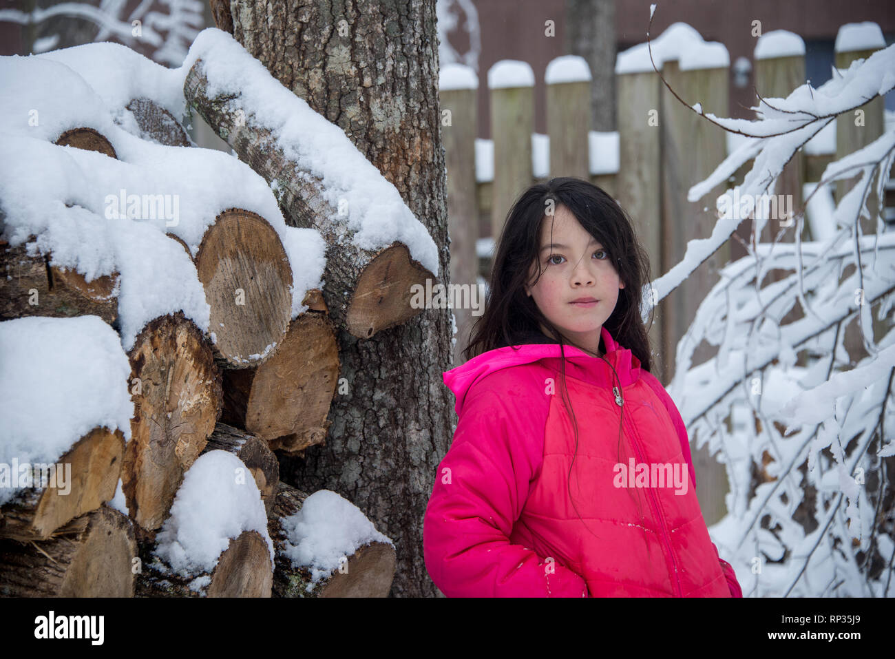 Junge asiatische Mädchen in rosa Fell neben Schnee auf einem Haufen anmelden Stockfoto
