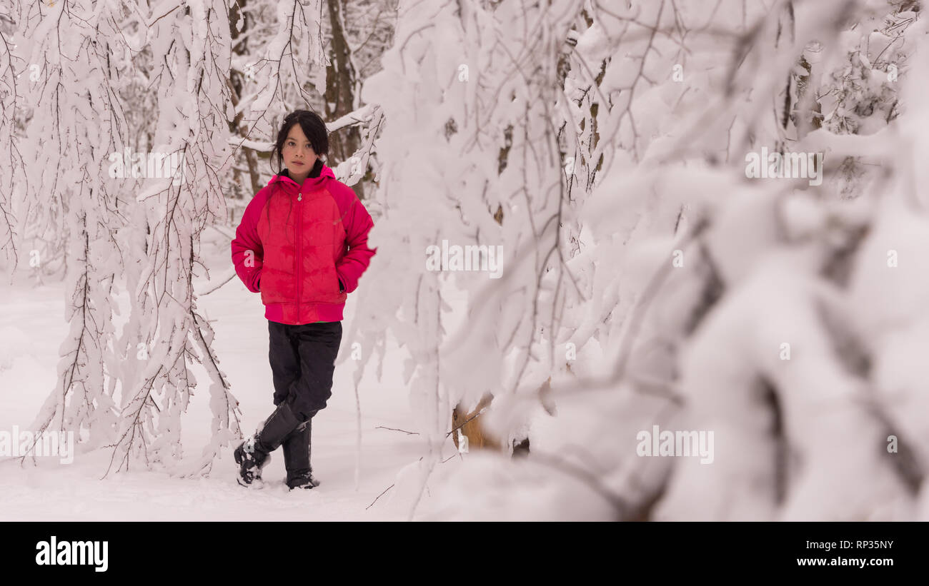 Junge Mädchen in rosa Jacke umgeben von Schnee bedeckt Stockfoto