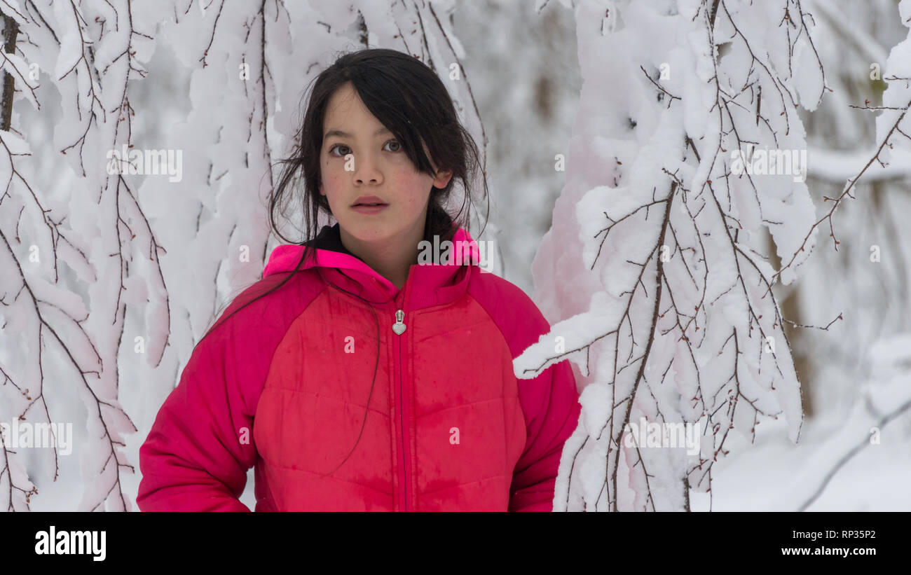 Jungen Asiatischen stehendes Mädchen im Schnee bedeckt Bäume in rosa Jacke Stockfoto