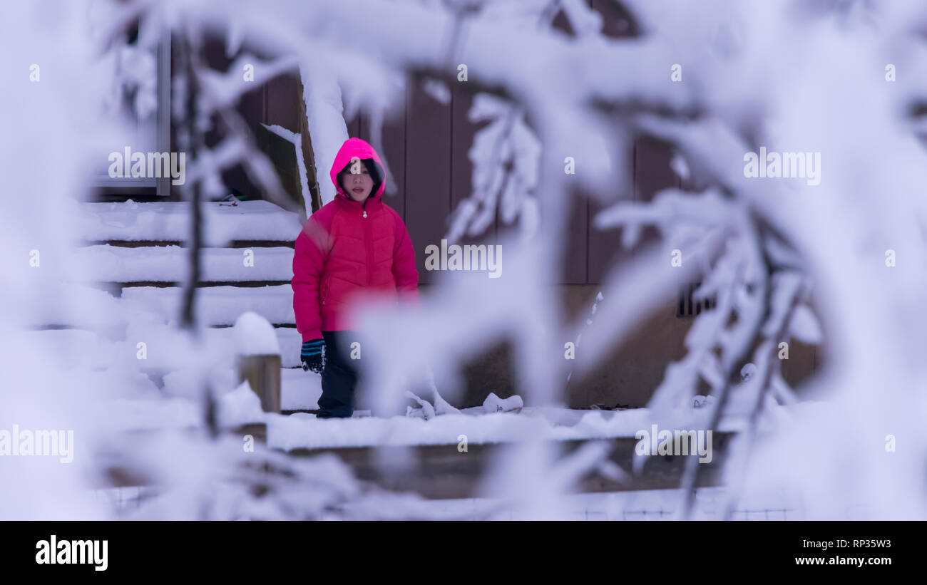 Junge Mädchen im Schnee bedeckt Bäume mit rosa Jacke Stockfoto