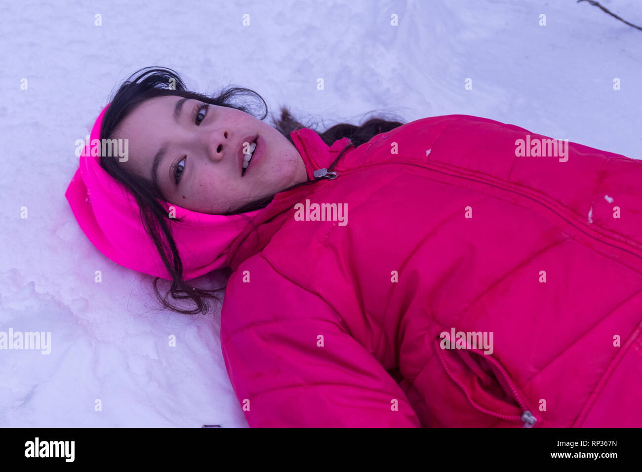 Junge asiatische Mädchen mit in den Schnee mit rosa Haube und Jacke Stockfoto