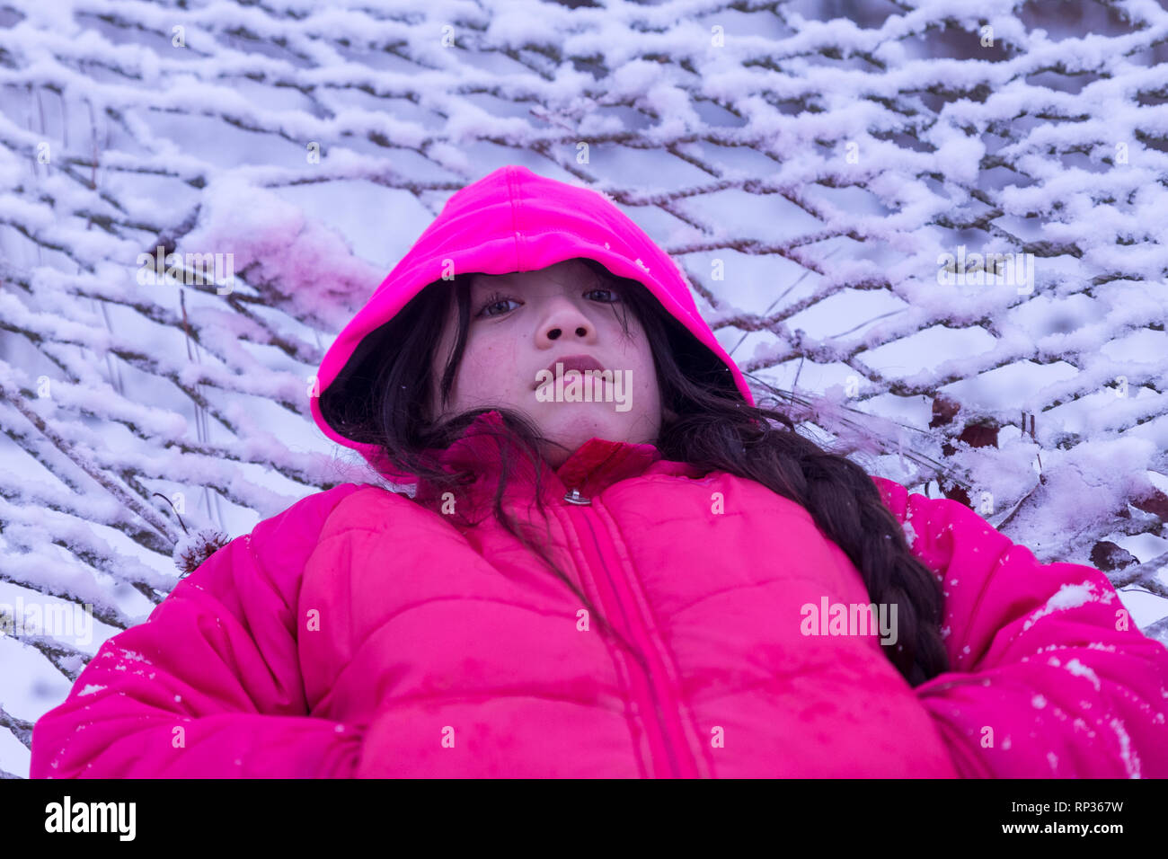 Junge asiatische Mädchen mit in den Schnee mit rosa Haube und Jacke Stockfoto