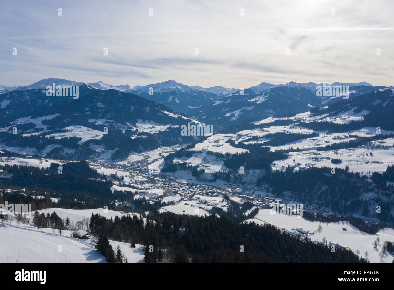 Blick von einer Drohne auf einem kleinen Dorf unter Winter Berge bedeckt mit Wäldern und Schnee in den Alpen. Stockfoto