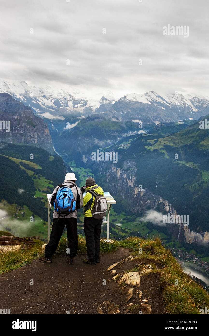 Wandern Paar auf männlichen Blick hinunter in die spektakuläre Lauterbrunnental, Berner Oberland, Schweiz Stockfoto