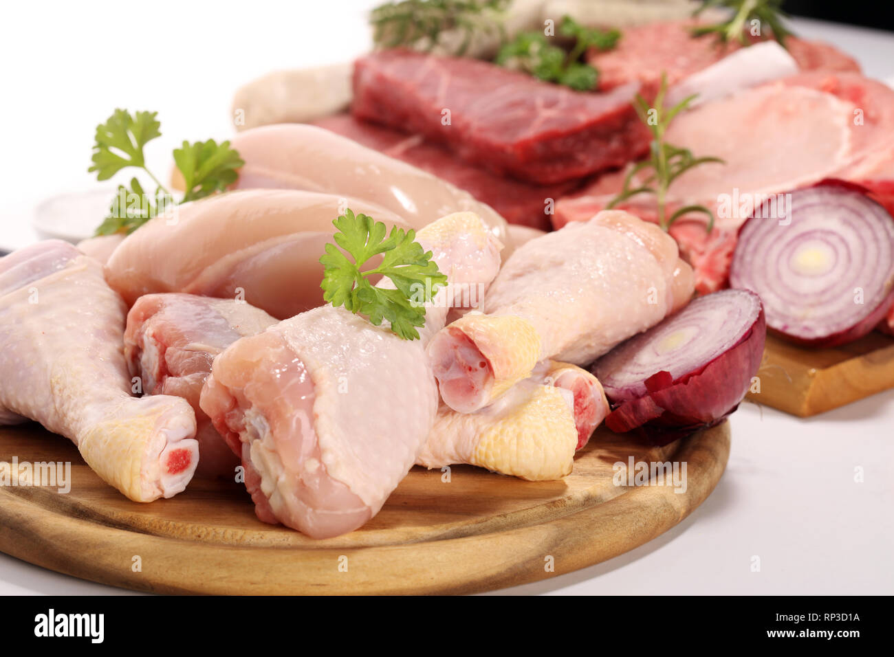 Rohes Fleisch. Verschiedene Arten von rohem Schweinefleisch, Hühnchen und Rindfleisch mit Gewürzen und Kräutern und Würstchen Stockfoto
