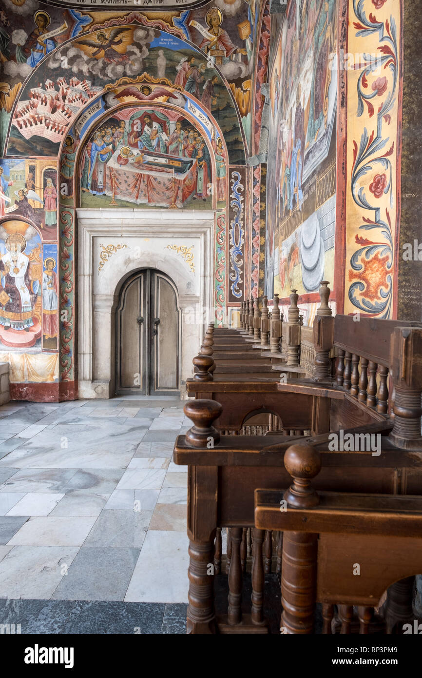 Holzbänke führen zu Holz- seitliche Tür der wichtigsten Kirche der Rila-kloster, Bulgarien. Alle Wände sind mit bunten religiösen Fresken und Gemälde gemalt Stockfoto