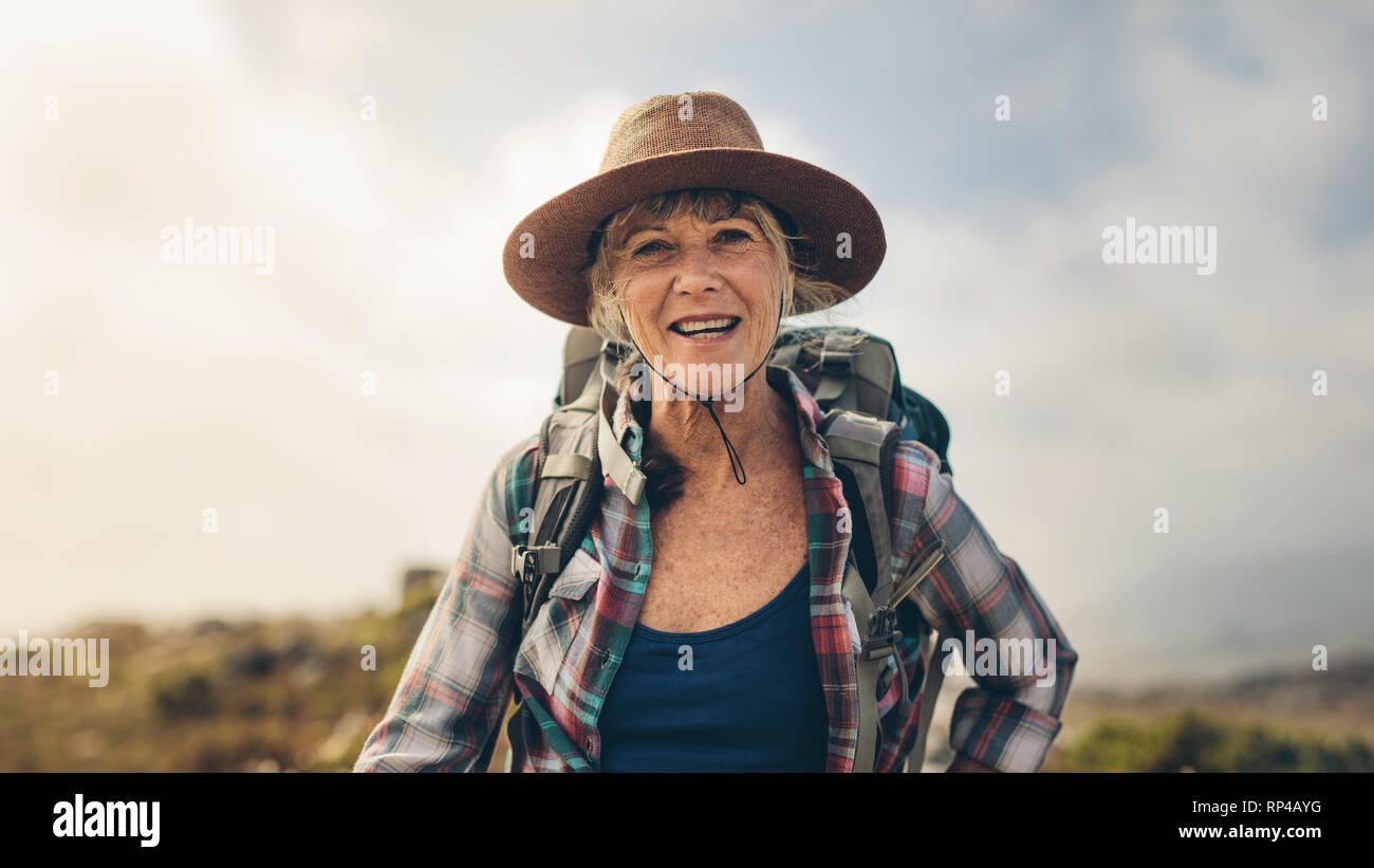 Fröhliche Frau genießen Sie Ihre Wanderung stand im Freien. Porträt einer Frau mit Hut und Rucksack auf einen Urlaub. Stockfoto