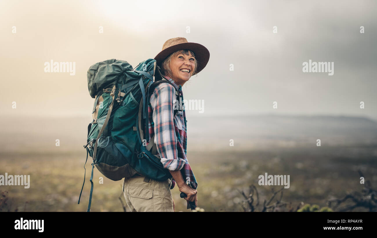 Seitenansicht eines älteren Frau Rucksack tragen auf einem Hügel beim  Trekking. Lächelnd senior Frau während einer Wanderung Kampagne aufgeregt  Stockfotografie - Alamy