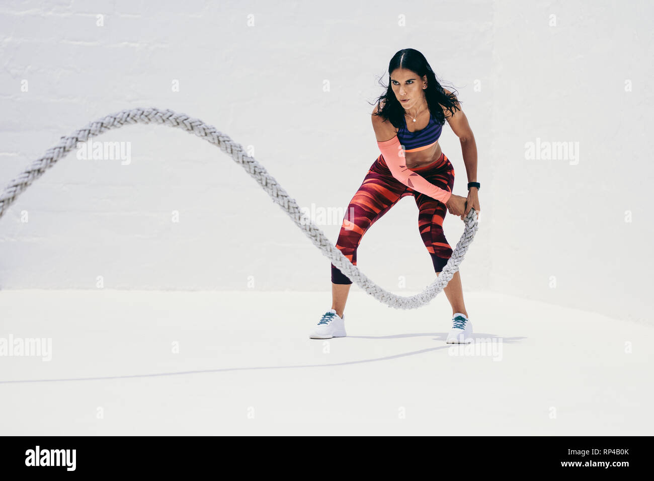 Fitness-Frau, die Krafttraining mit Kampfseil macht. Athletische Frau, die mit Kampfseil trainieren muss. Stockfoto