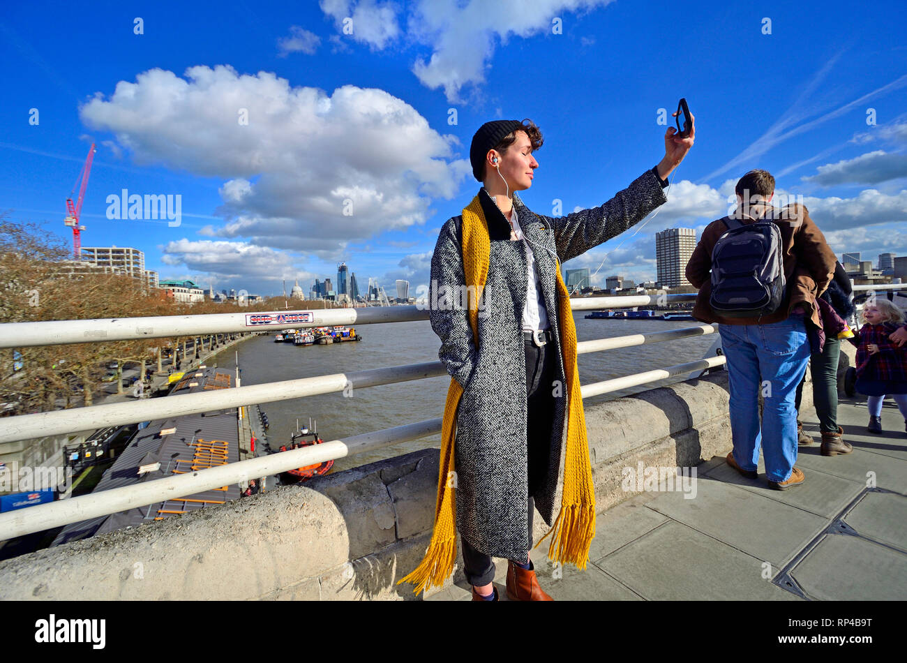 London, England, UK. Junge Frau mit einem selfie auf der Waterloo Bridge an einem sonnigen Tag im Februar 2019 Stockfoto