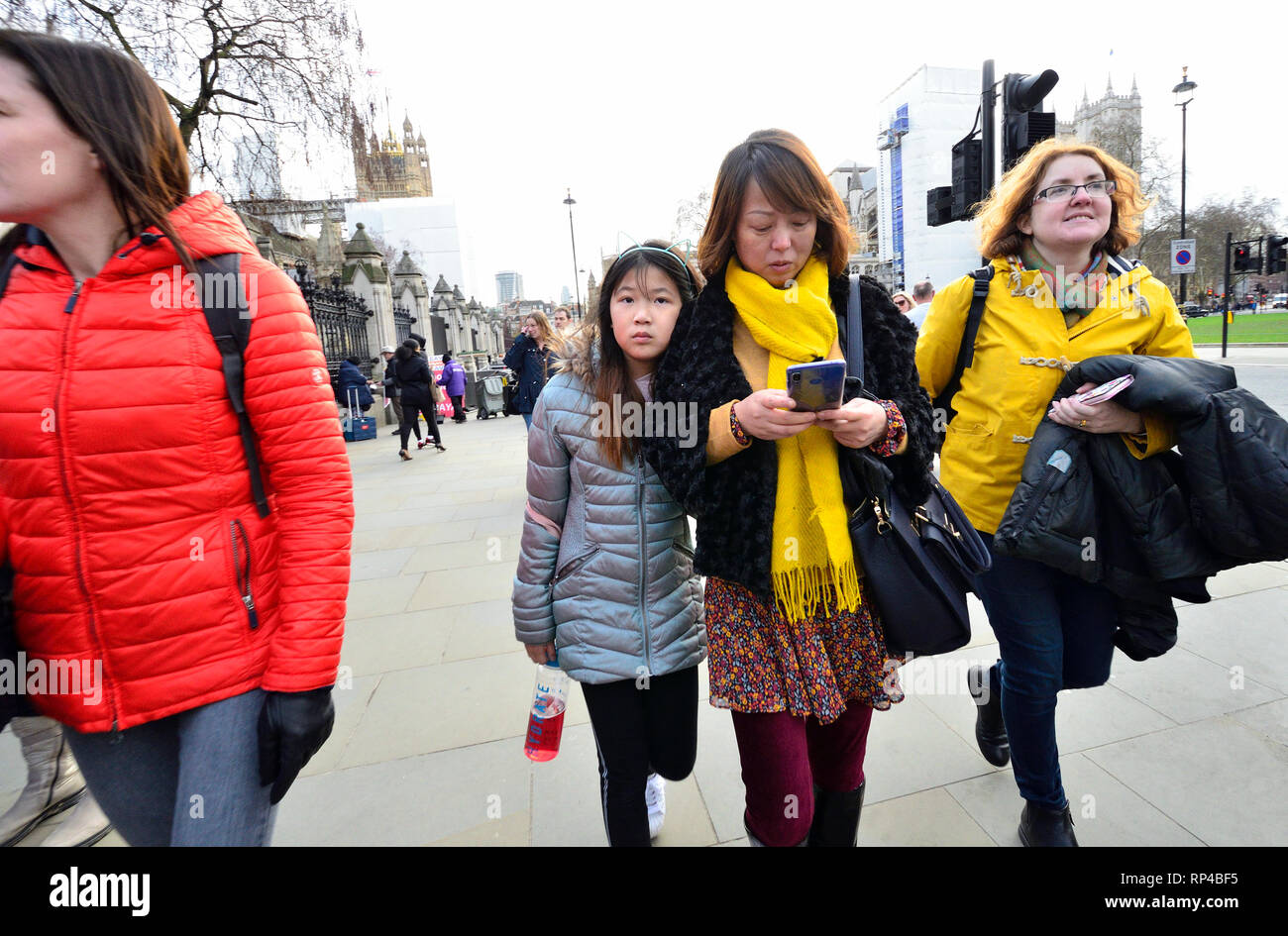 London, England, UK. Asiatische Mutter und Tochter zu Fuß auf der Straße - die Mutter an ihr Mobiltelefon suchen, Parliament Square Stockfoto