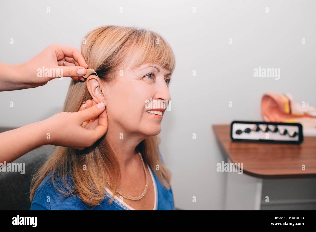 Die Anpassung eines Hörgerätes für eine ausgereifte womans Ohr Stockfoto