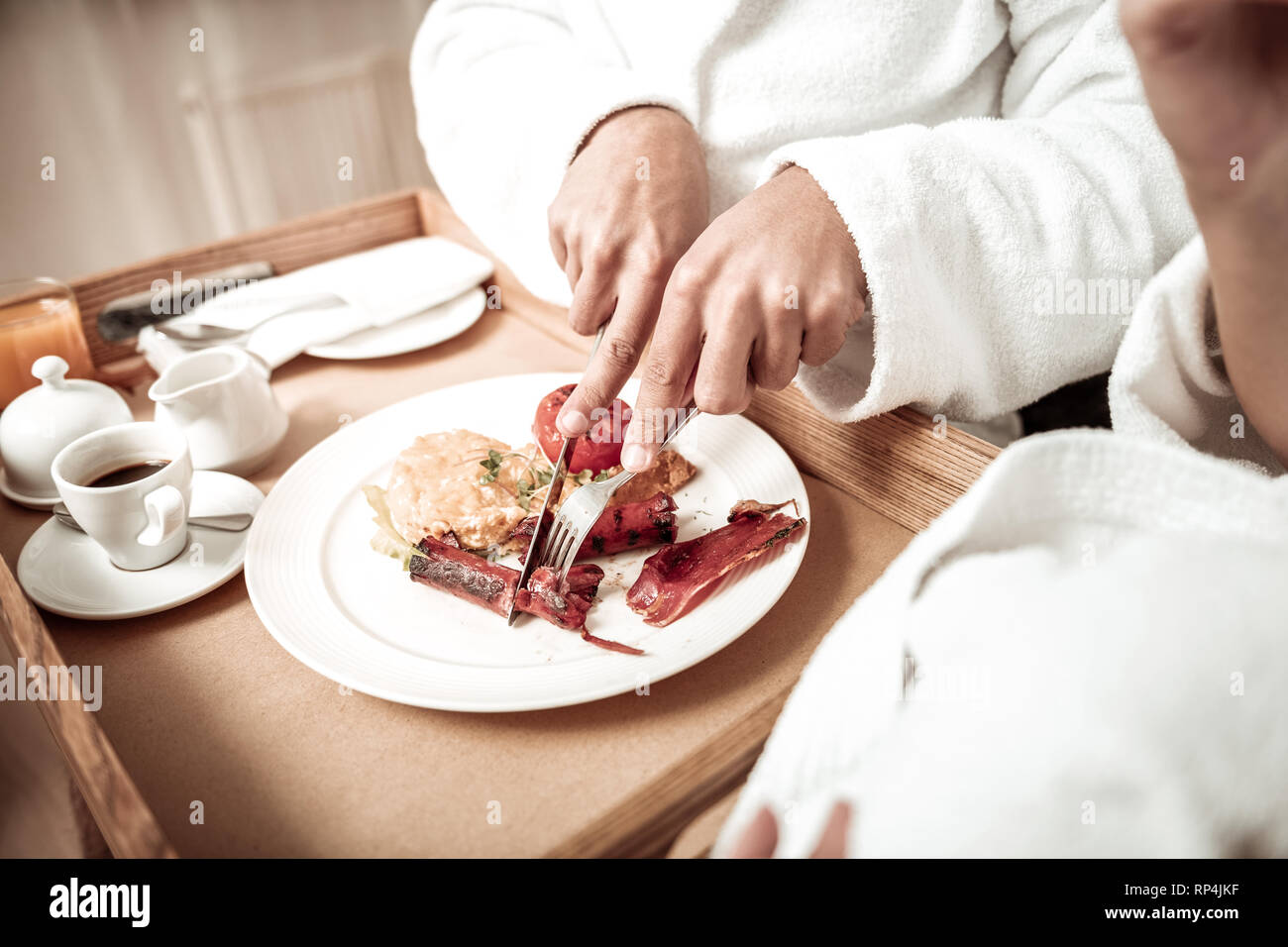 Nahaufnahme von Mann, Bademantel schneiden Wurst mit Frühstück Stockfoto