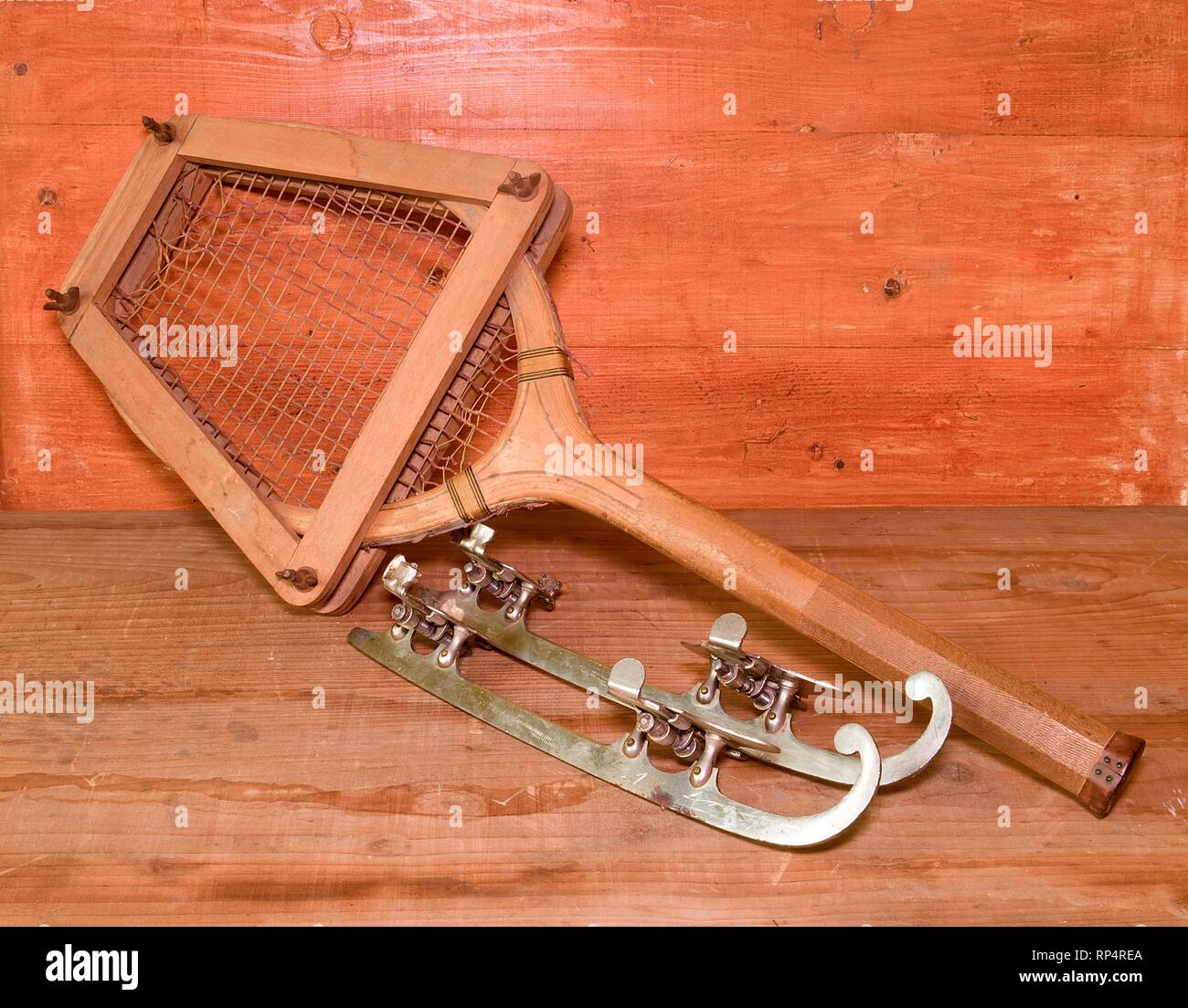 Vintage Schlittschuhe und Tennisschläger auf Holz- Hintergrund. Retro Schlittschuhe und Tennisschläger. Stockfoto