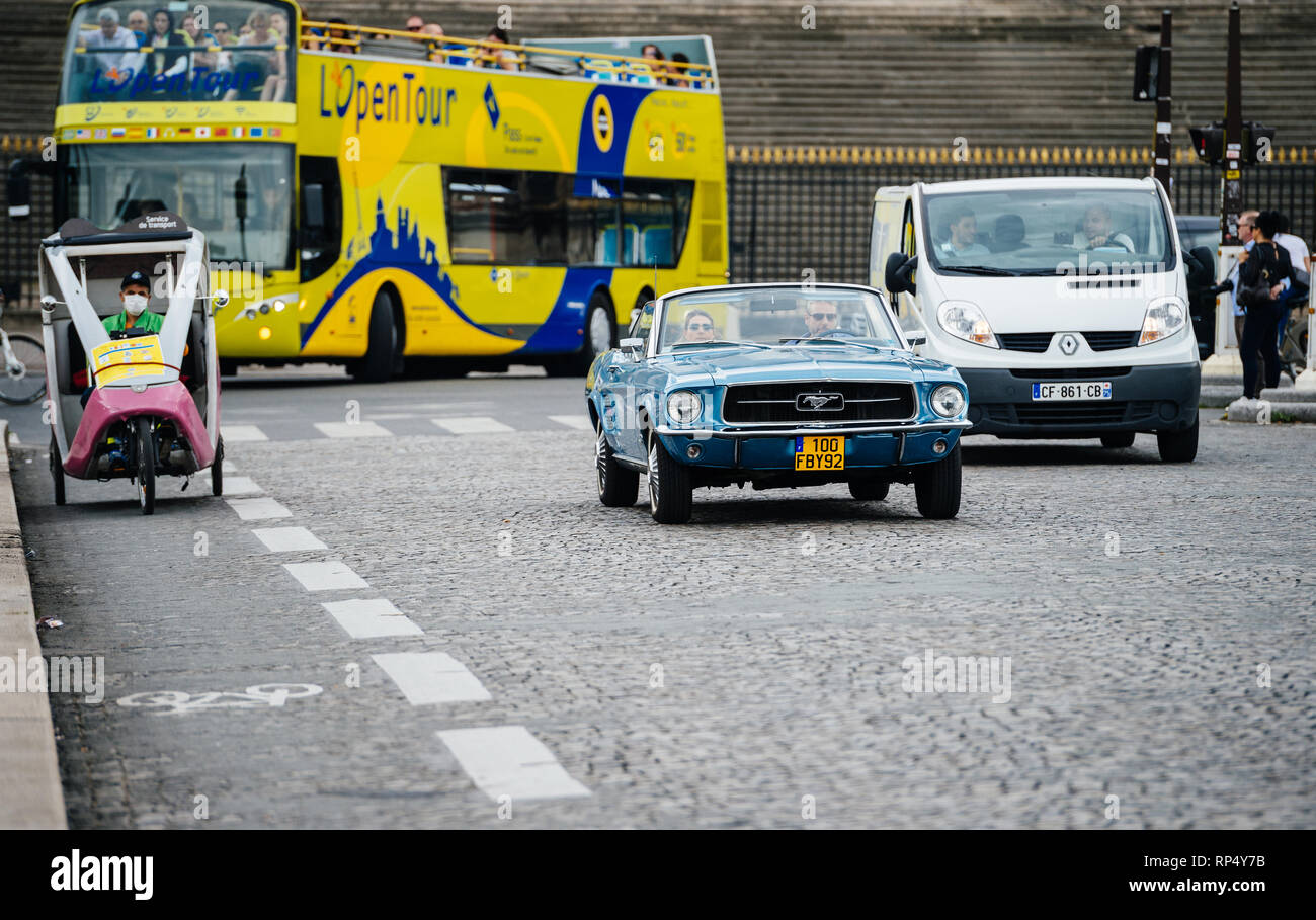 PARIS, Frankreich, 21. MAI 2016: Paar in vintage Mustang und Mann mit Schutz Maske Fahren seines Rikscha auf Paris Street - hohe Luftverschmutzung Stockfoto