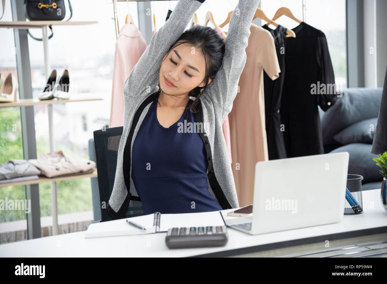 Asiatische kreative Designer stretching Arme und Auge vor Laptop auf Schreibtisch Stockfoto