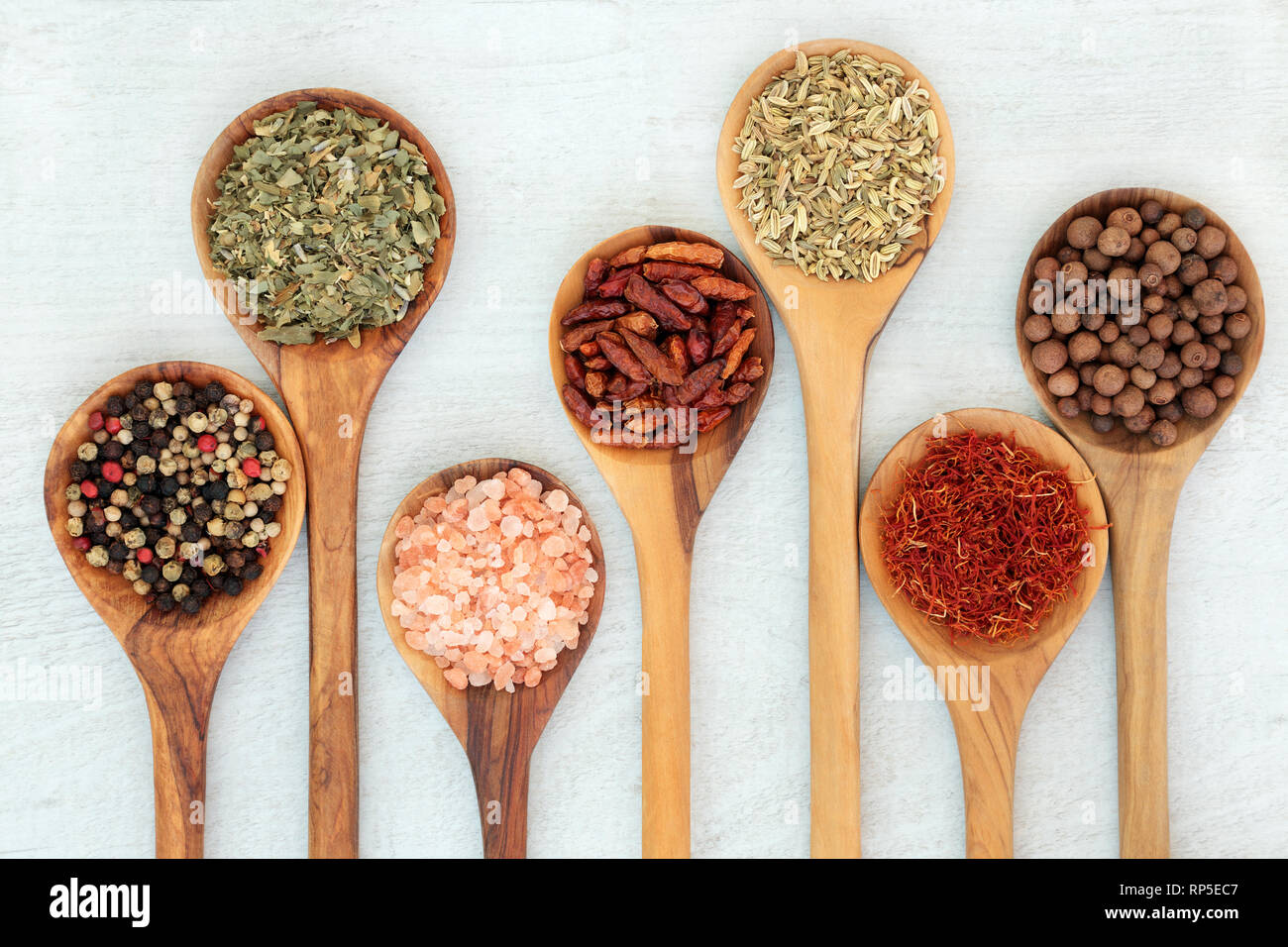 Kräuter & Gewürze essen Gewürz in Olivenholz Löffel. Nach rechts Pfefferkörner Links, Kräuter der Provence, Salz, Paprika, Fenchel, Safran und Piment. Stockfoto