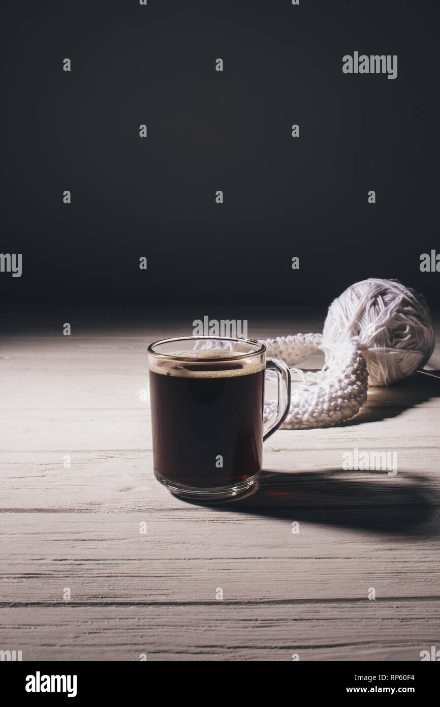 Tasse schwarzen Kaffee auf Tisch neben Stricken arbeiten. Stockfoto