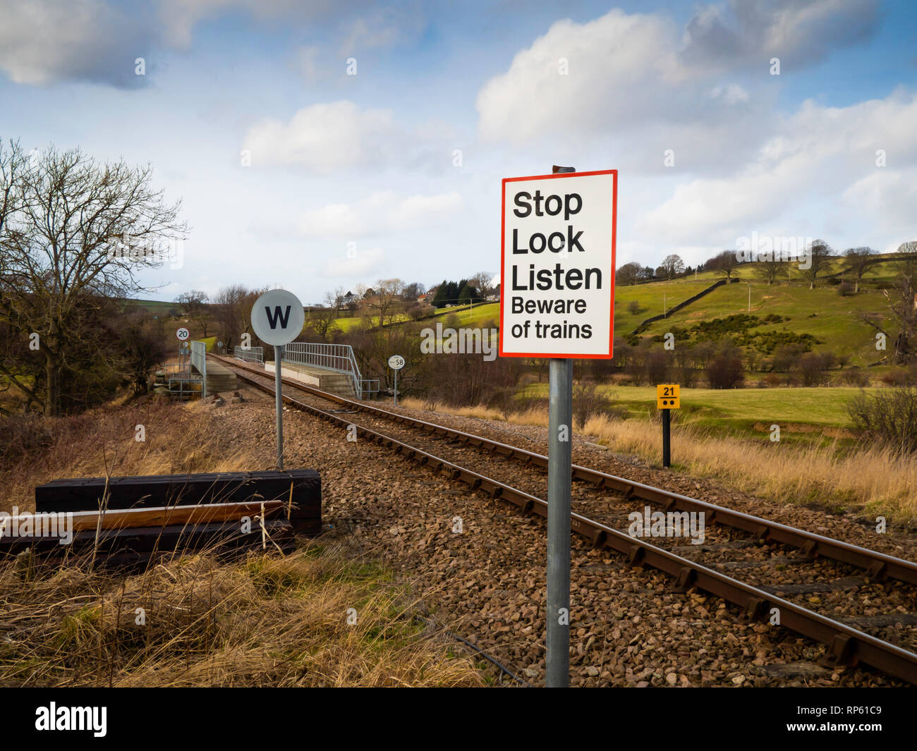 Un-gated Bahnübergang zeichen Stop Look Listen Vorsicht vor Züge, eine obligatorische Trillerpfeife Zeichen für den Zug und 20 mph Höchstgeschwindigkeit auf der Brücke voran Stockfoto