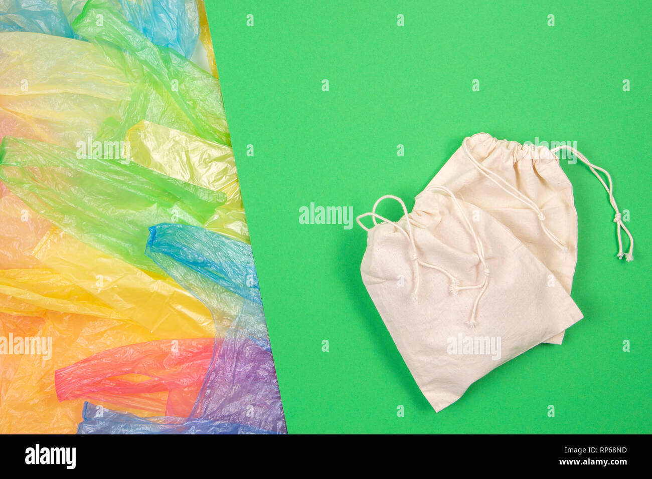 Viele bunte Plastiktüten mit einem eco-natürliche, wiederverwendbare Tasche zum Einkaufen auf grünem Hintergrund. Null Abfall, Umweltfreundlich, kein Plastik Konzept Stockfoto