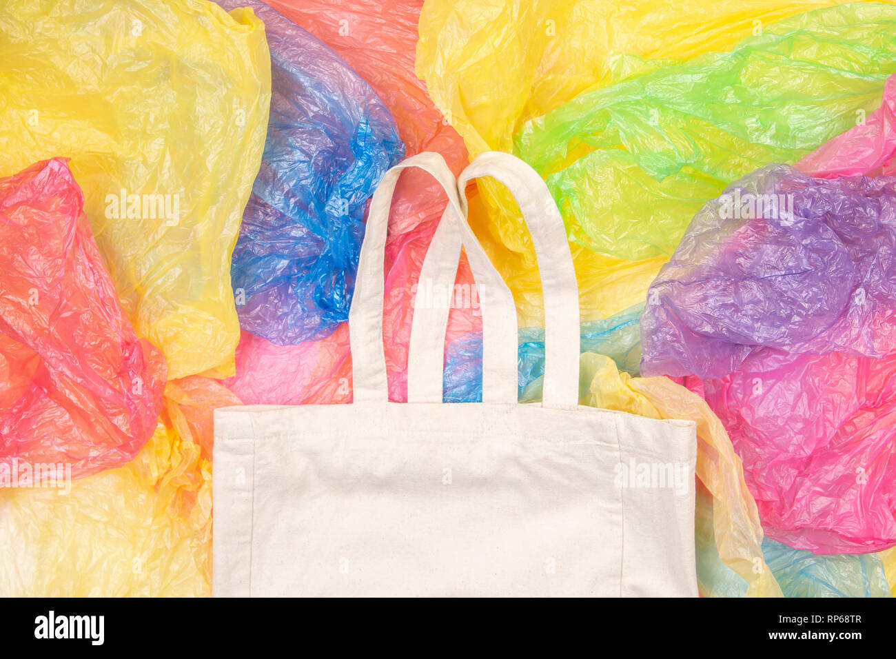 Viele bunte Plastiktüten mit einem eco-natürliche, wiederverwendbare Tasche zum Einkaufen. Null Abfall, Umweltfreundlich, kein Plastik Konzept Stockfoto