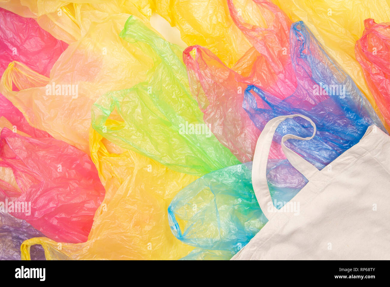 Viele bunte Plastiktüten mit einem eco-natürliche, wiederverwendbare Tasche zum Einkaufen. Null Abfall, Umweltfreundlich, kein Plastik Konzept Stockfoto