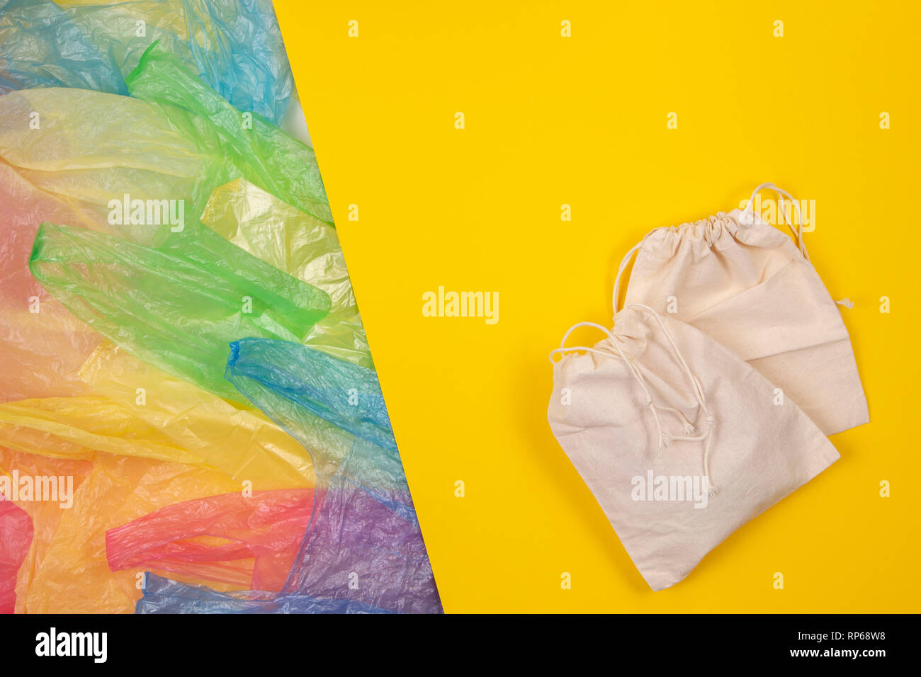 Viele bunte Plastiktüten mit einem eco-natürlichen wiederverwendbare Tasche für den Einkauf auf gelben Hintergrund. Null Abfall, Umweltfreundlich, kein Plastik Konzept Stockfoto