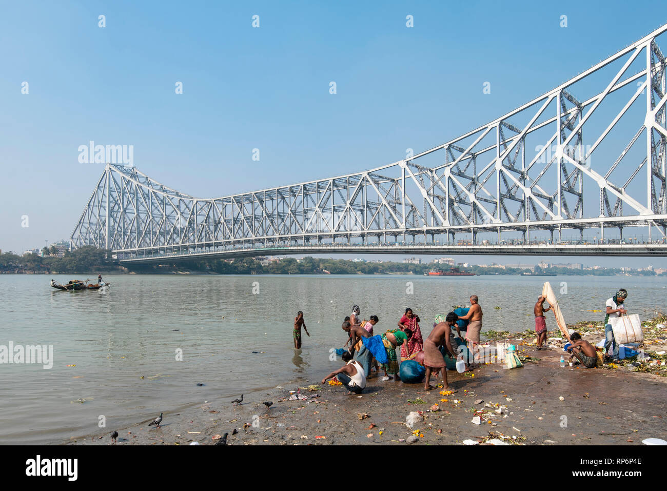 Howrah Bridge - im Volksmund bekannt als die Rabindra Setu mit Blick auf den Mullick Ghat mit Einheimischen baden Waschen an einem sonnigen Tag und blauer Himmel. Stockfoto