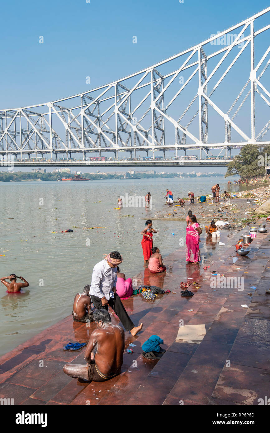 Howrah Bridge - im Volksmund bekannt als die Rabindra Setu mit Blick auf den Mullick Ghat mit Einheimischen baden Waschen an einem sonnigen Tag und blauer Himmel. Stockfoto