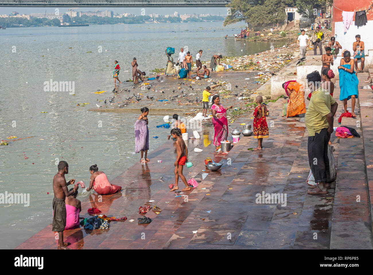 Die Mullick Ghat neben der Howrah Bridge mit Einheimischen baden Waschen an einem sonnigen Tag und blauer Himmel. Stockfoto