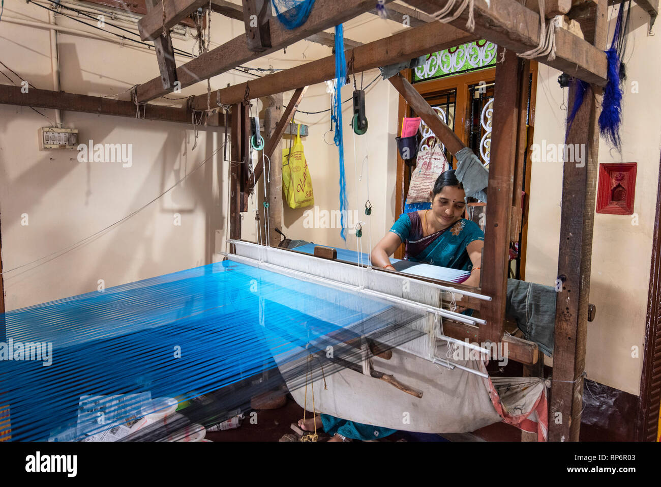 Eine lokale indische Frau arbeiten mit einem traditionellen Handwebstühlen und Seide Material für einen Saree in Ihrem kleinen Laden. Stockfoto