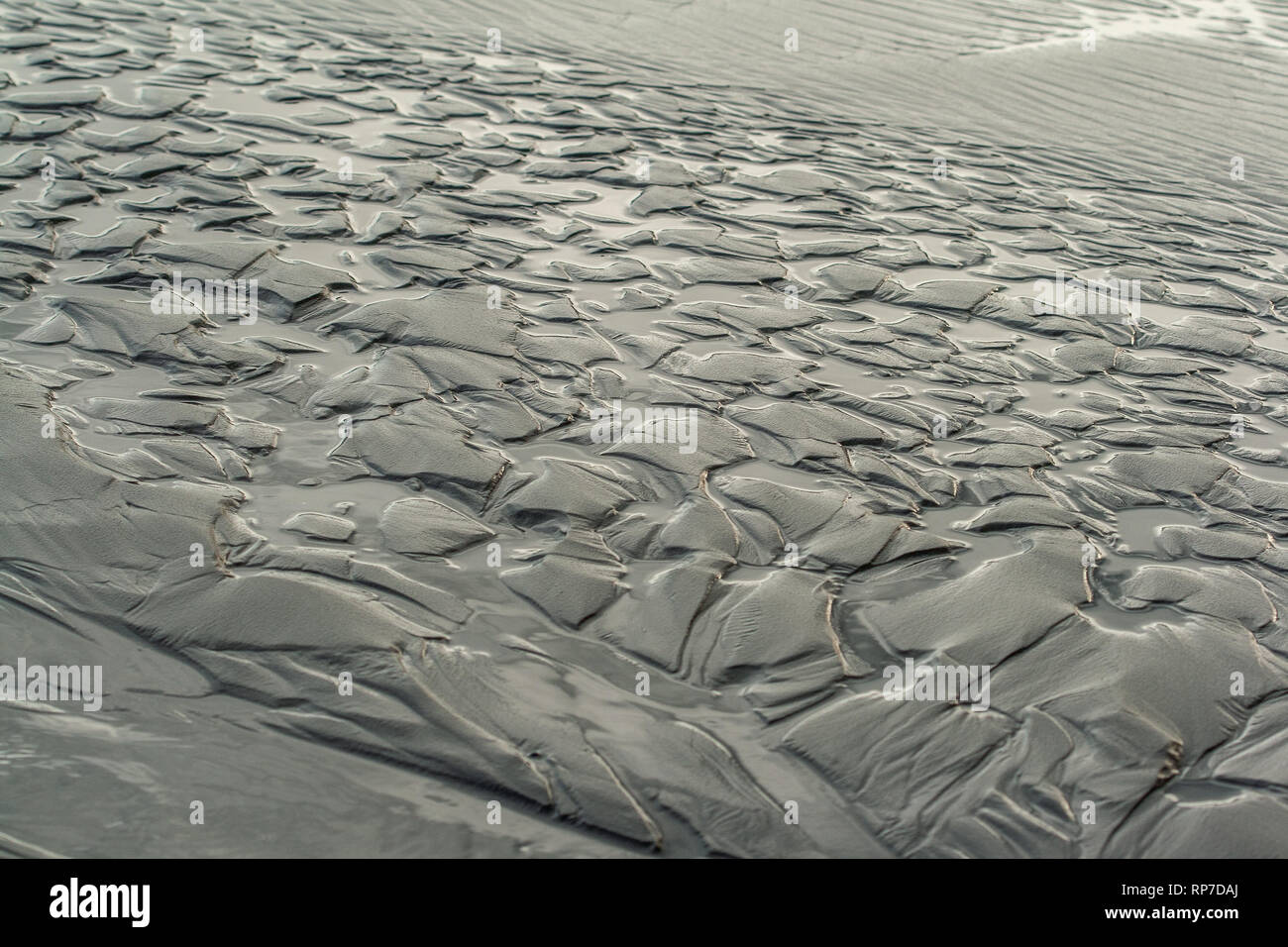 Zurückziehende Wellen lassen Muster in den Sand am Strand in Olympic National Park Stockfoto