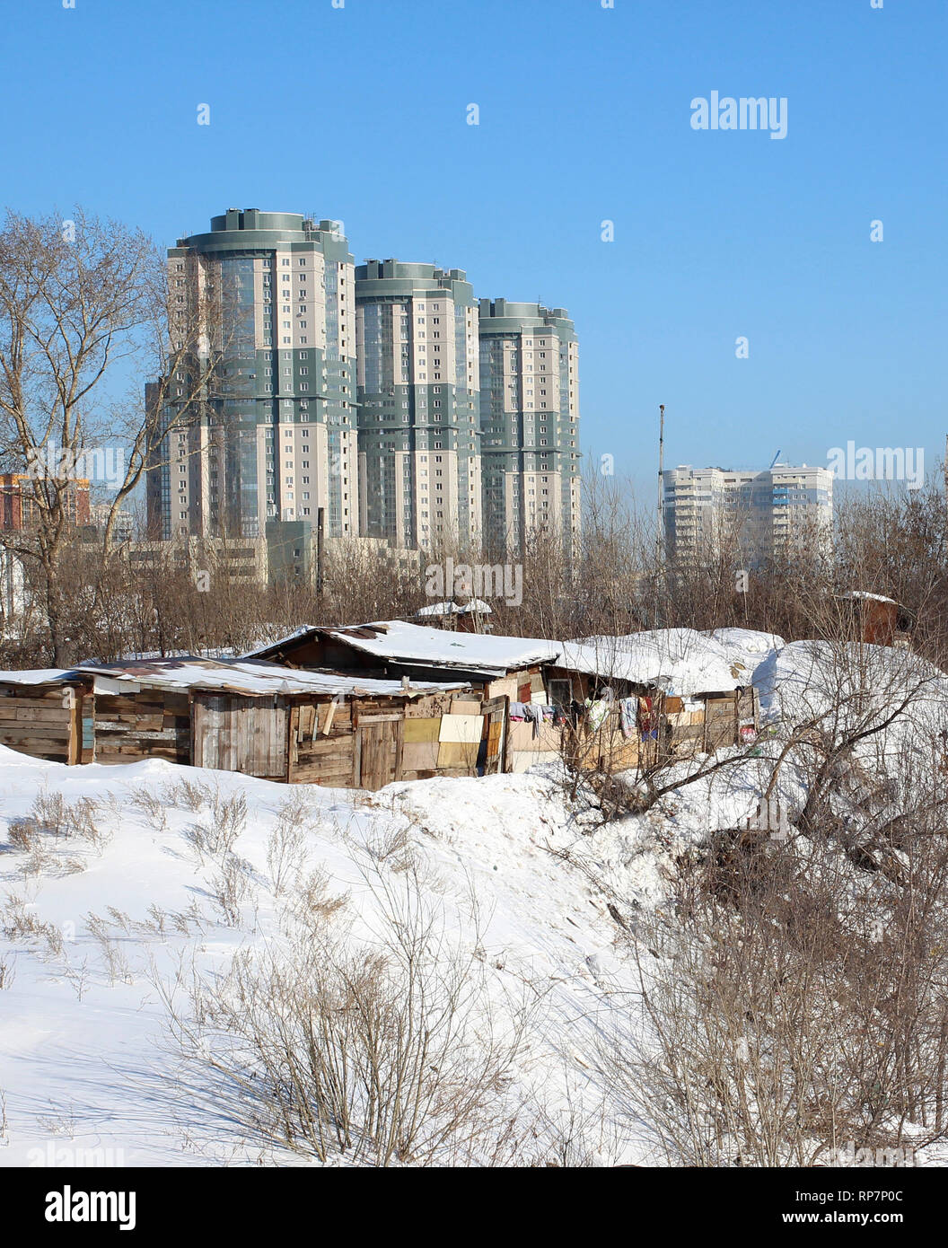 Hohes modernes Gebäude Hochhäuser steigen über die historischen Bauten der Holzhäuser im Winter Novosibirsk historische Stockfoto