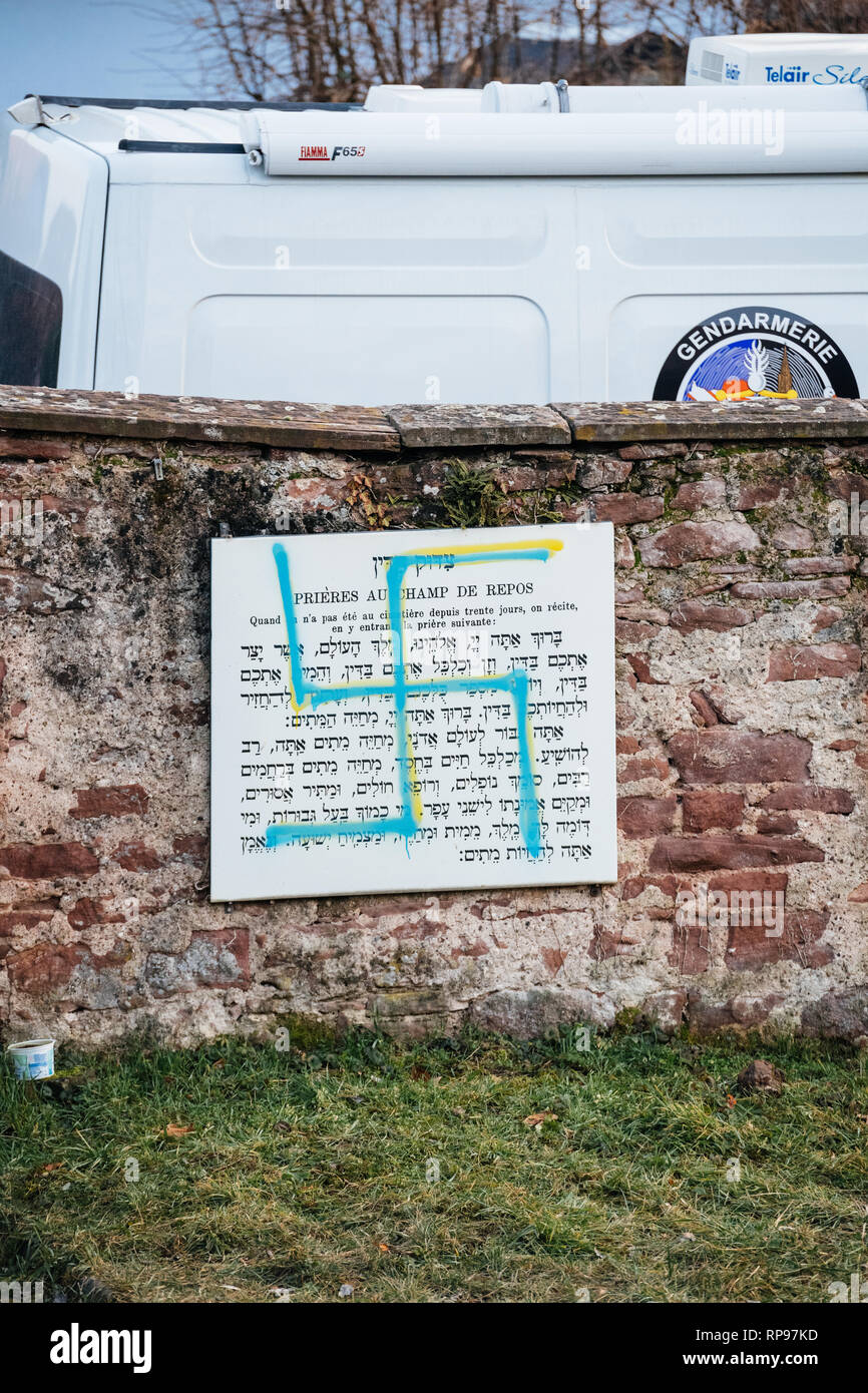 Quatzenheim, Frankreich - Feb 20, 2019: Vandalismus am Beten Stein mit NS-Symbolen in blau Spray-painted Jüdischen Friedhof in Quatzenheim in der Nähe von Straßburg - Spezielle gendarmerie Polizei Überwachung van im Hintergrund Stockfoto