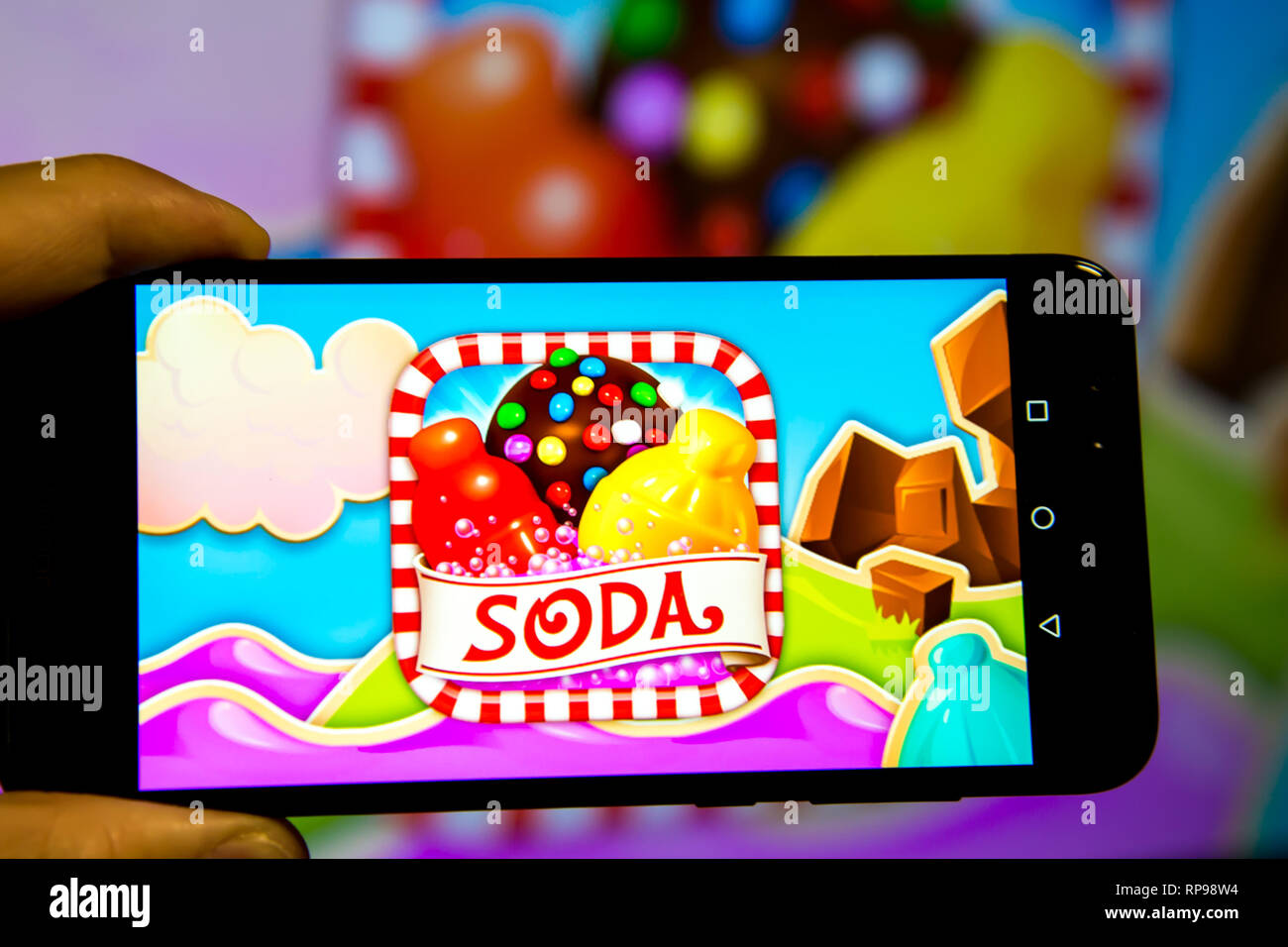 Los Angeles, Kalifornien, USA - 21. Februar 2019: Hände, die ein Smartphone mit Candy Crush SAGA Spiel gegen die großen Bildschirm. Stockfoto