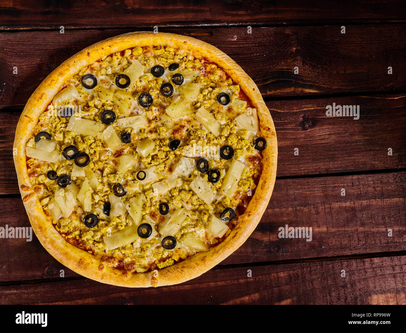 Leckere Pizza mit Huhn und Ananas auf einem Holztisch Stockfoto