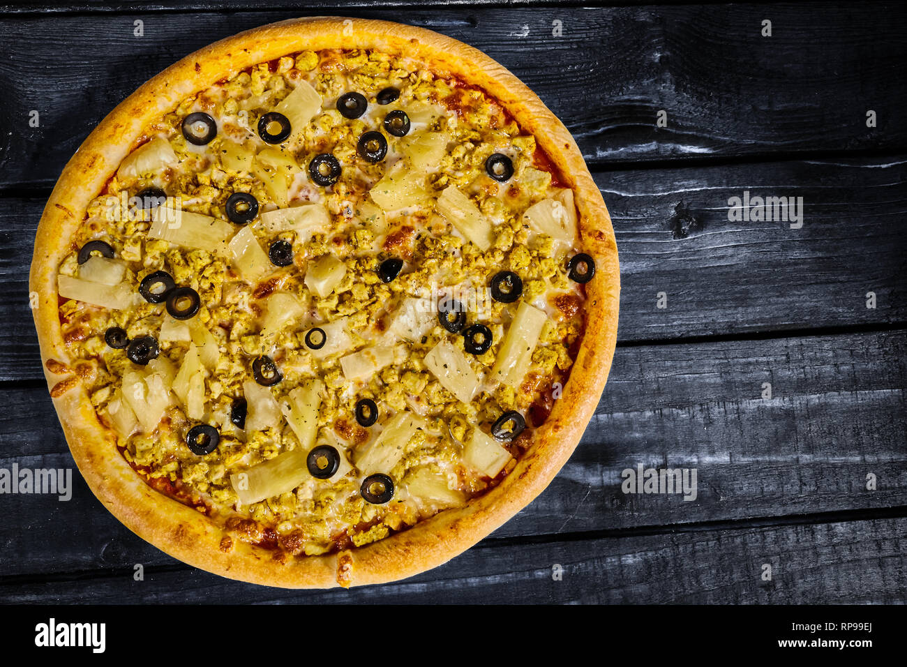 Leckere Pizza mit Huhn und Ananas auf einem Holztisch Stockfoto