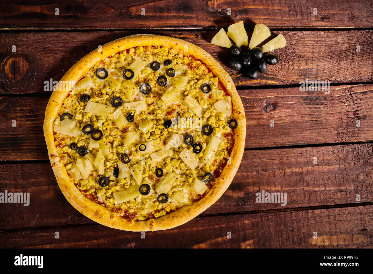 Pizza mit Huhn und Ananas auf einem Holztisch Stockfoto