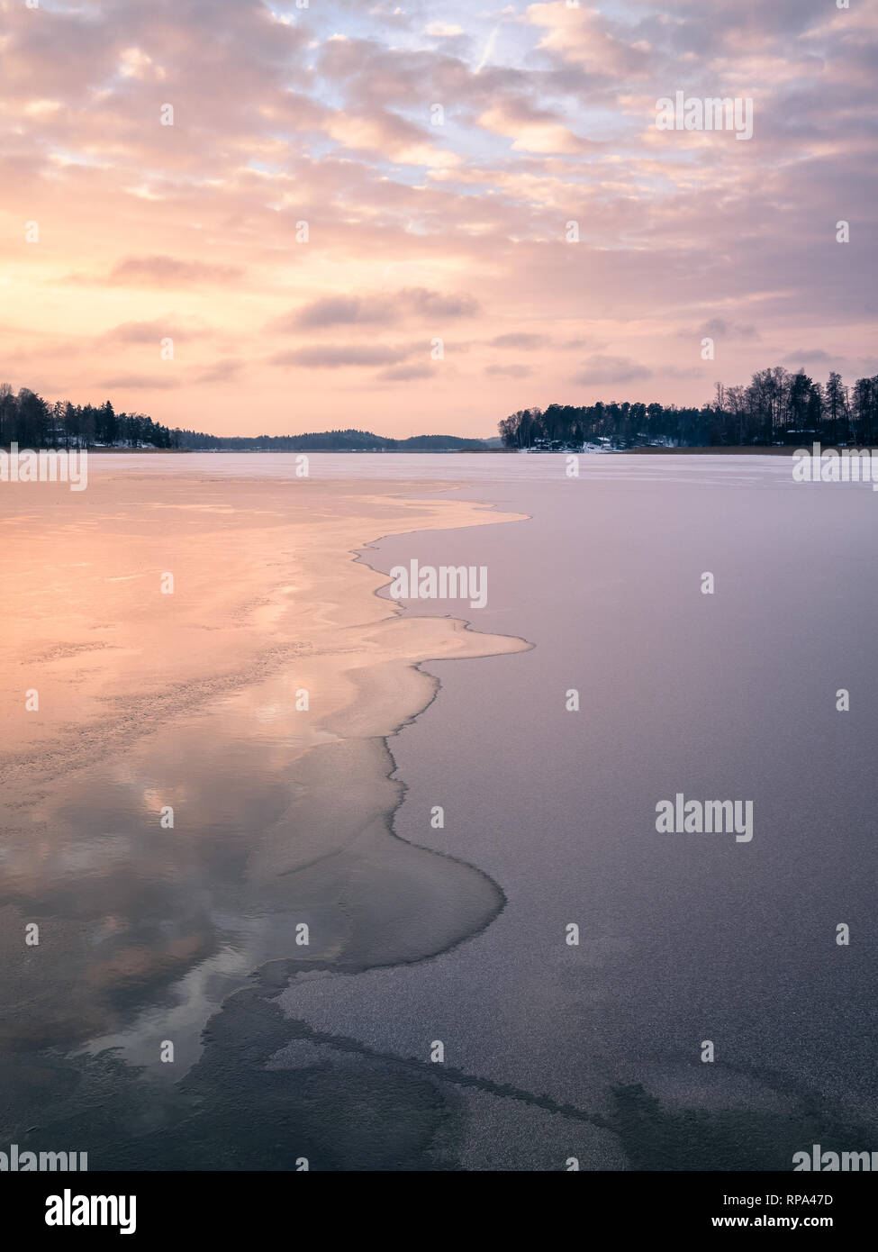 Malerische Winterlandschaft mit gefrorenen See und Wasser am Abend Sonnenuntergang in Finnland Stockfoto