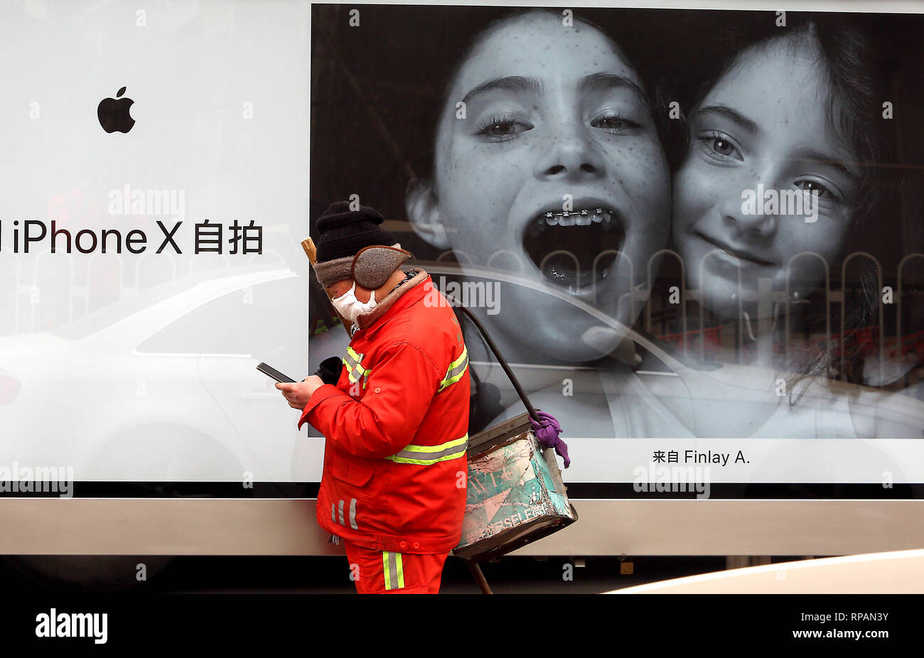 April 7, 2018 - Peking, China - ein chinesischer Street Sweeper nutzt sein Handy vor ein iPhone X Werbung in Peking am 7. April 2018. Das chinesische Ministerium für Handel sagte, daß es plant, eine um 25 Prozent auf $ 50 Mrd. von US-Exporten zu verhängen. (Bild: © Todd Lee/ZUMAprilESS.com/ZUMA Draht) Stockfoto